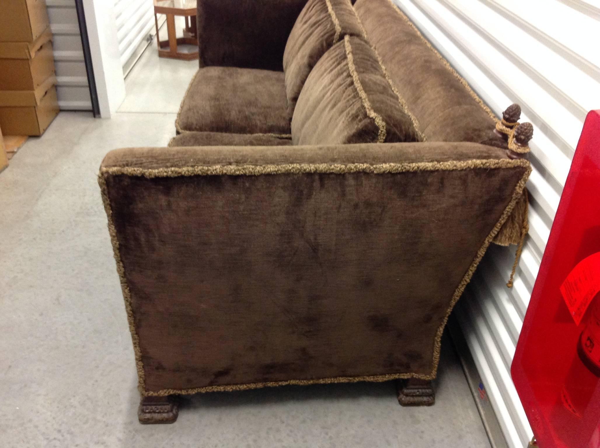 This 1930s-1940s Knole sofa with carved finials with tassels and intricately carved feet features drop sides in original brown velvet upholstery with fringe surrounding the sofa and pillows. This unsual Knole sofa is comfortable and in excellent