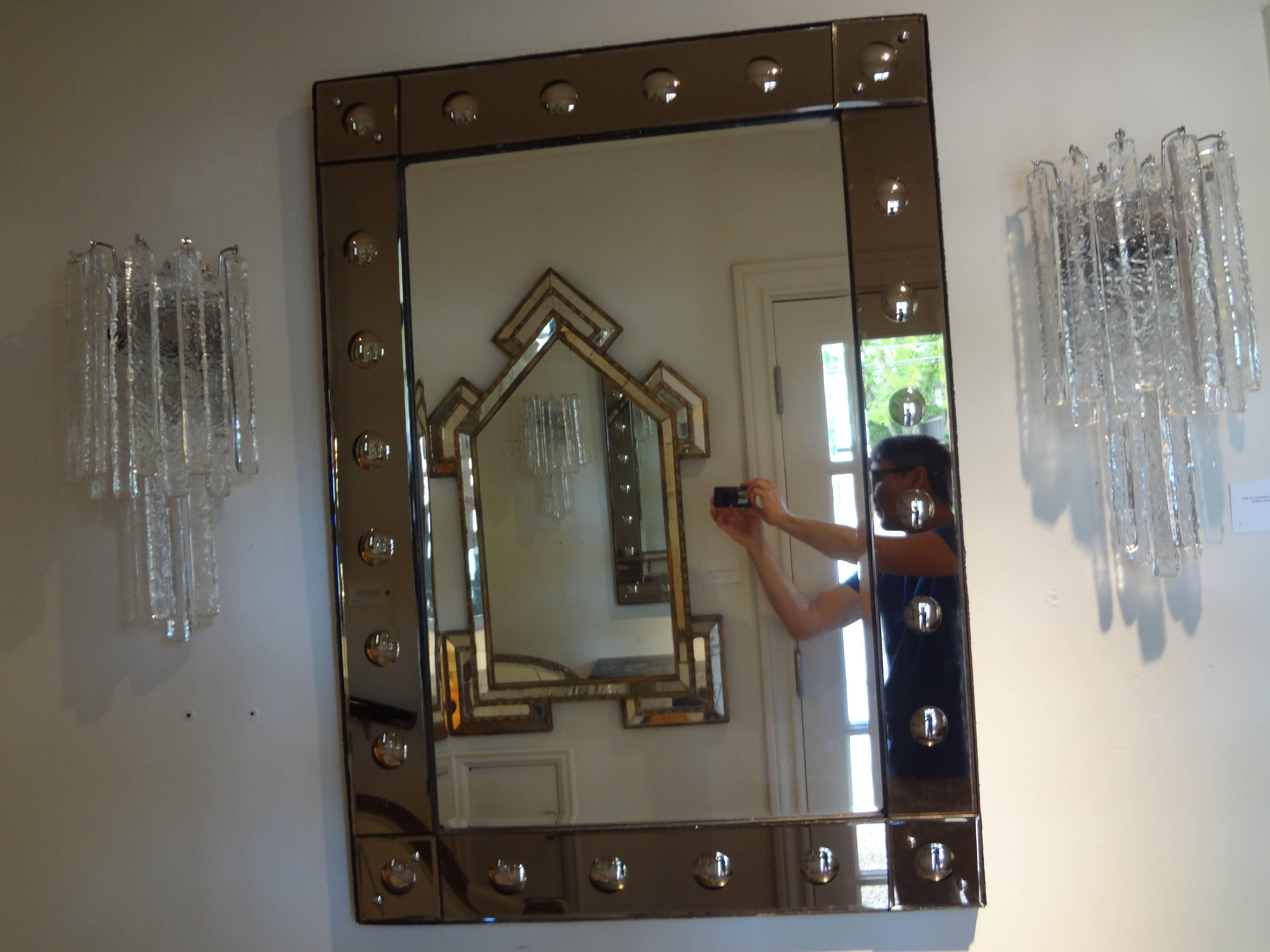 Mid-century rectangular beveled bronze Venetian mirror.
Unusual vintage Venetian mirror with a bronze border and convex circular bullseye detail surrounding a beveled silver mirrored center. This mirror can be hung either vertically or horizontally.