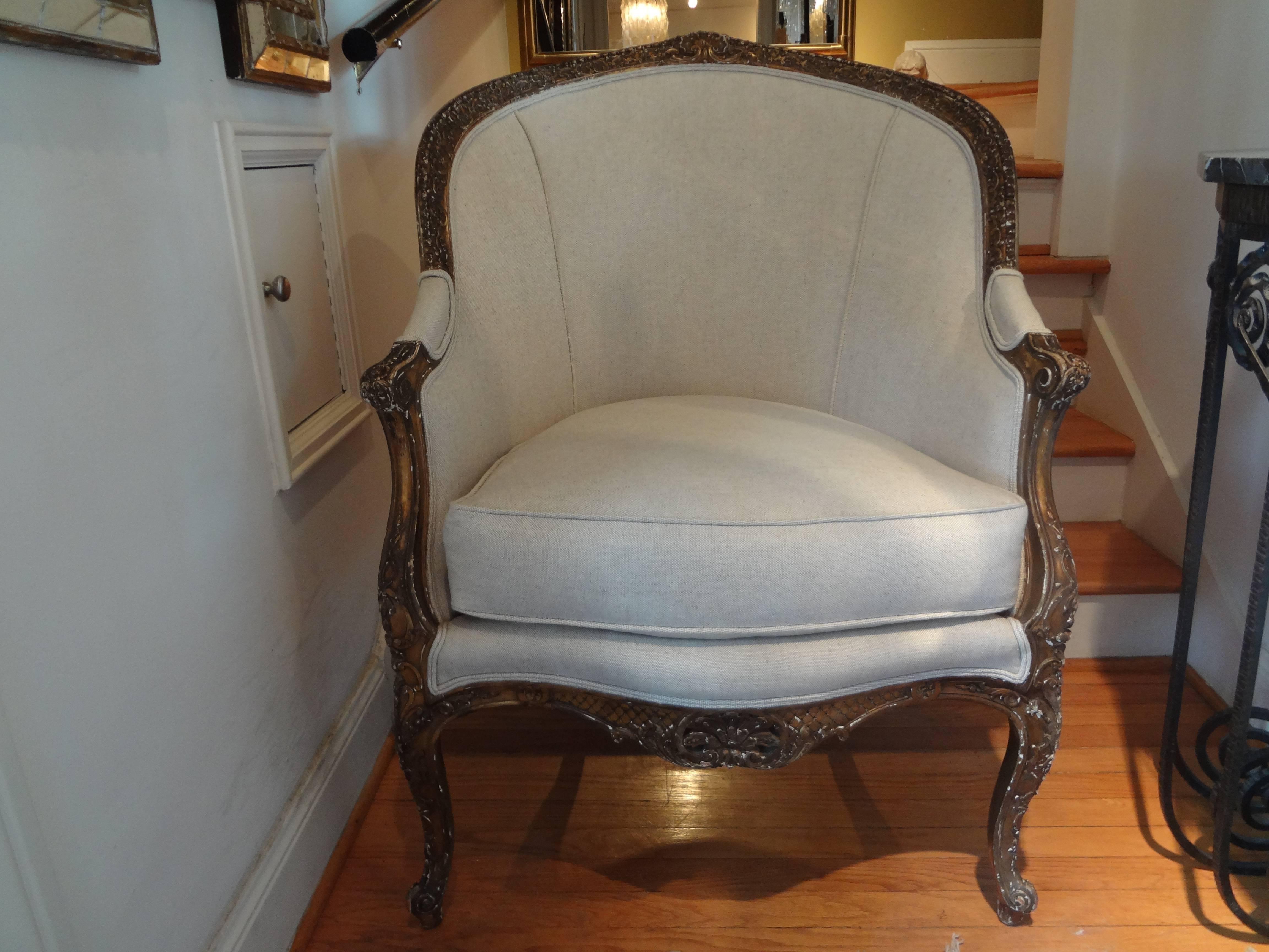 19th century French Regence style giltwood bergère.
Beautifully detailed and comfortable antique French Regence style gilt wood bergère chair newly upholstered in oatmeal linen. This stunning French Regence style giltwood bergère has a beautiful