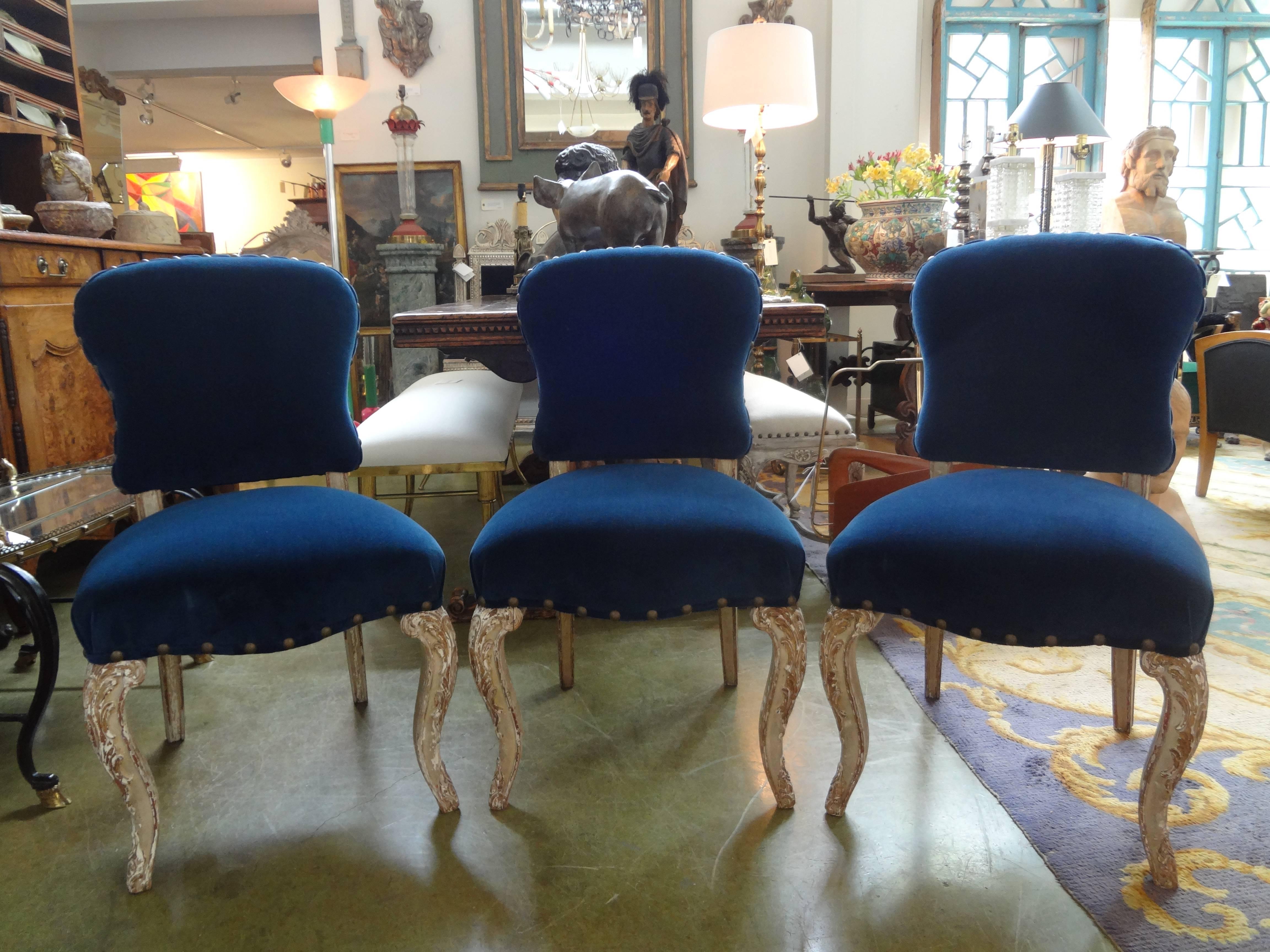 Stylish and comfortable set of six antique French Louis XV-XVI Style Maison Jansen attributed painted and gilt wood dining chairs with fabulous distressed patina. Taken down to frames and professionally reupholstered in dark blue velvet with spaced