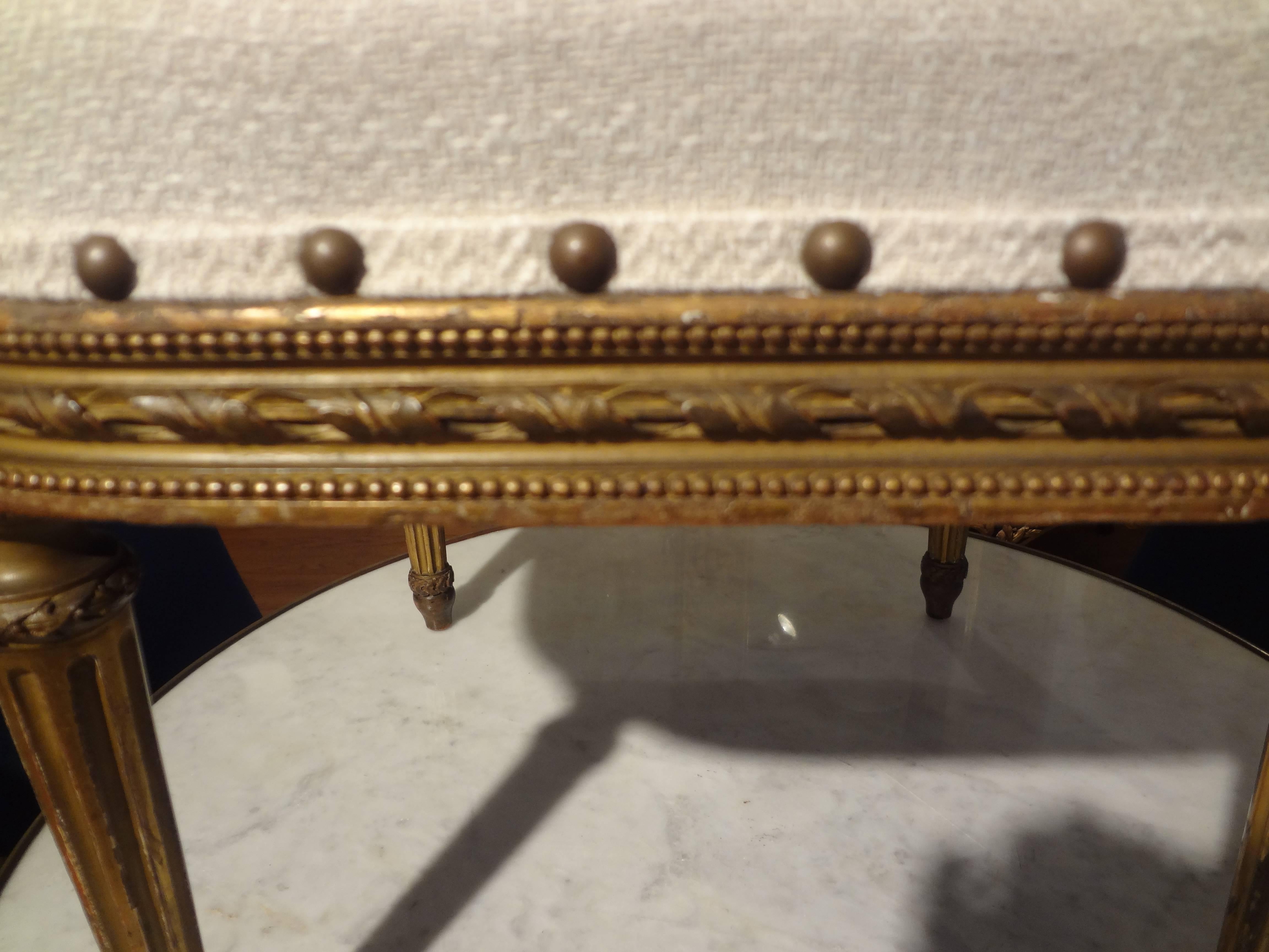 Unusually shaped antique French Louis XVI style giltwood tabouret, stool, ottoman or bench, professionally upholstered in cream colored linen blend with a loose cushion.