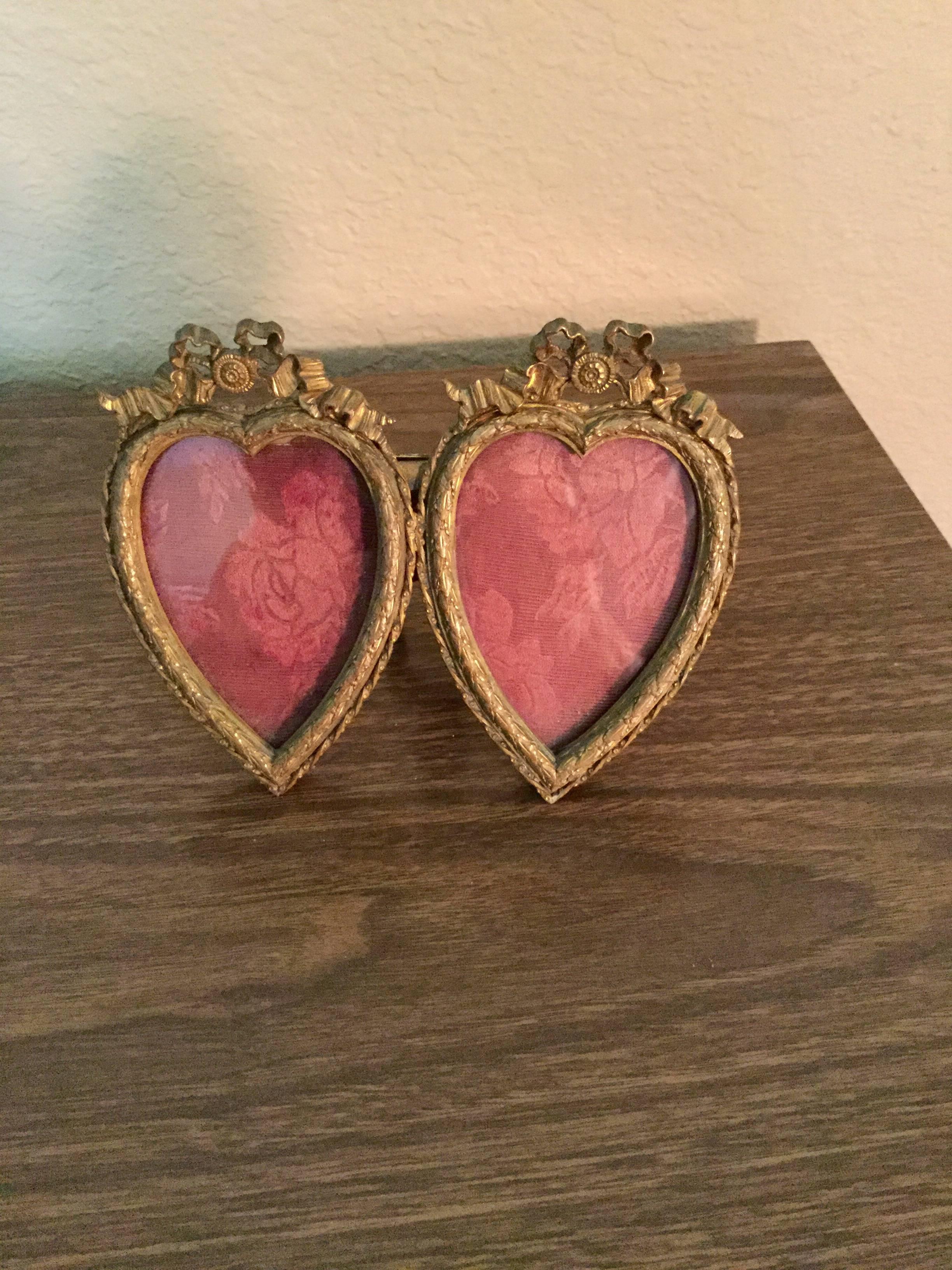 A rare antique French Louis XVI style bronze or brass double heart picture or photograph frame crowned with a French bow at the top of each heart. It has very fine detailing and gilding with leaves and berries and a twisted rope design around