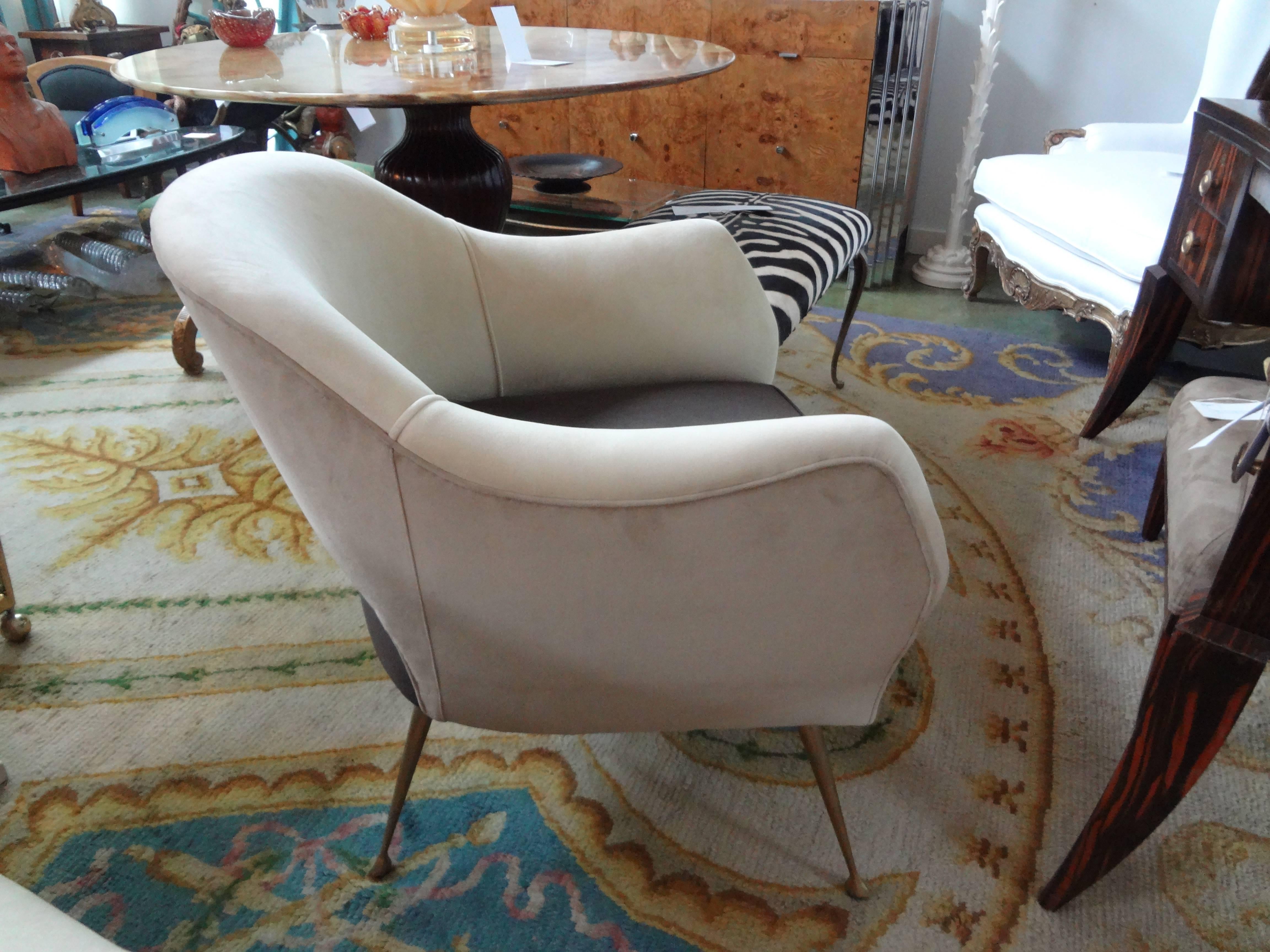 Unusual pair of Italian Mid-Century Modern lounge/club chairs by ISA Bergamo with splayed tapered brass legs and a partial open back. Upholstered in taupe and brown velvet fabric. These chairs offer comfort and style!