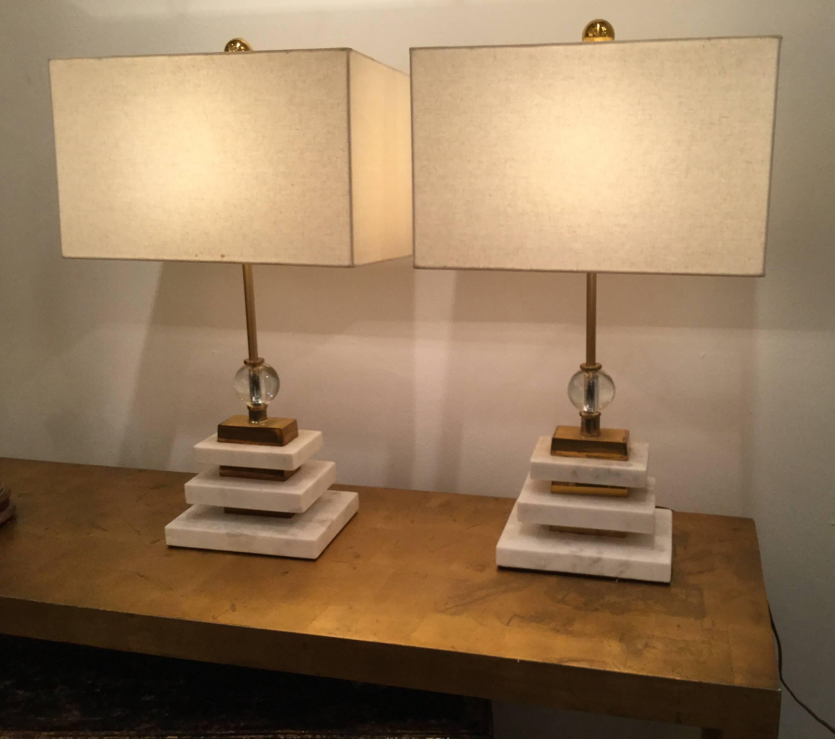 Pair of French Art Deco geometric style white marble table lamps with brass inserts between the marble and glass spheres at the top. Excellent quality, with original shades.