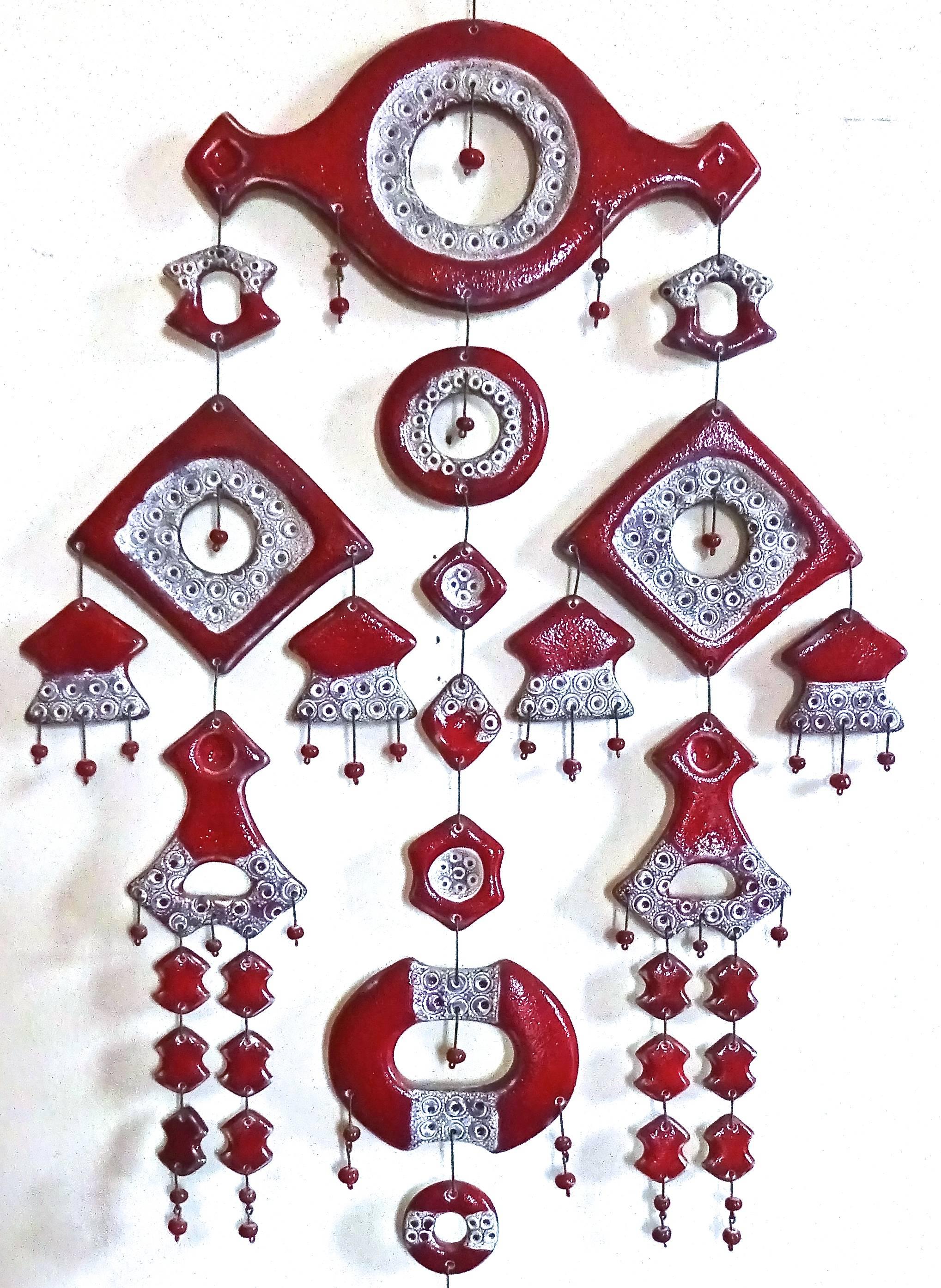 Wonderful and unusual art pottery hanging wall sculpture, made in Denmark in the late 1960's. This piece features 108 individual handmade pieces, done in a red flambé glaze with incised details in black and white. They are hand assembled with steel