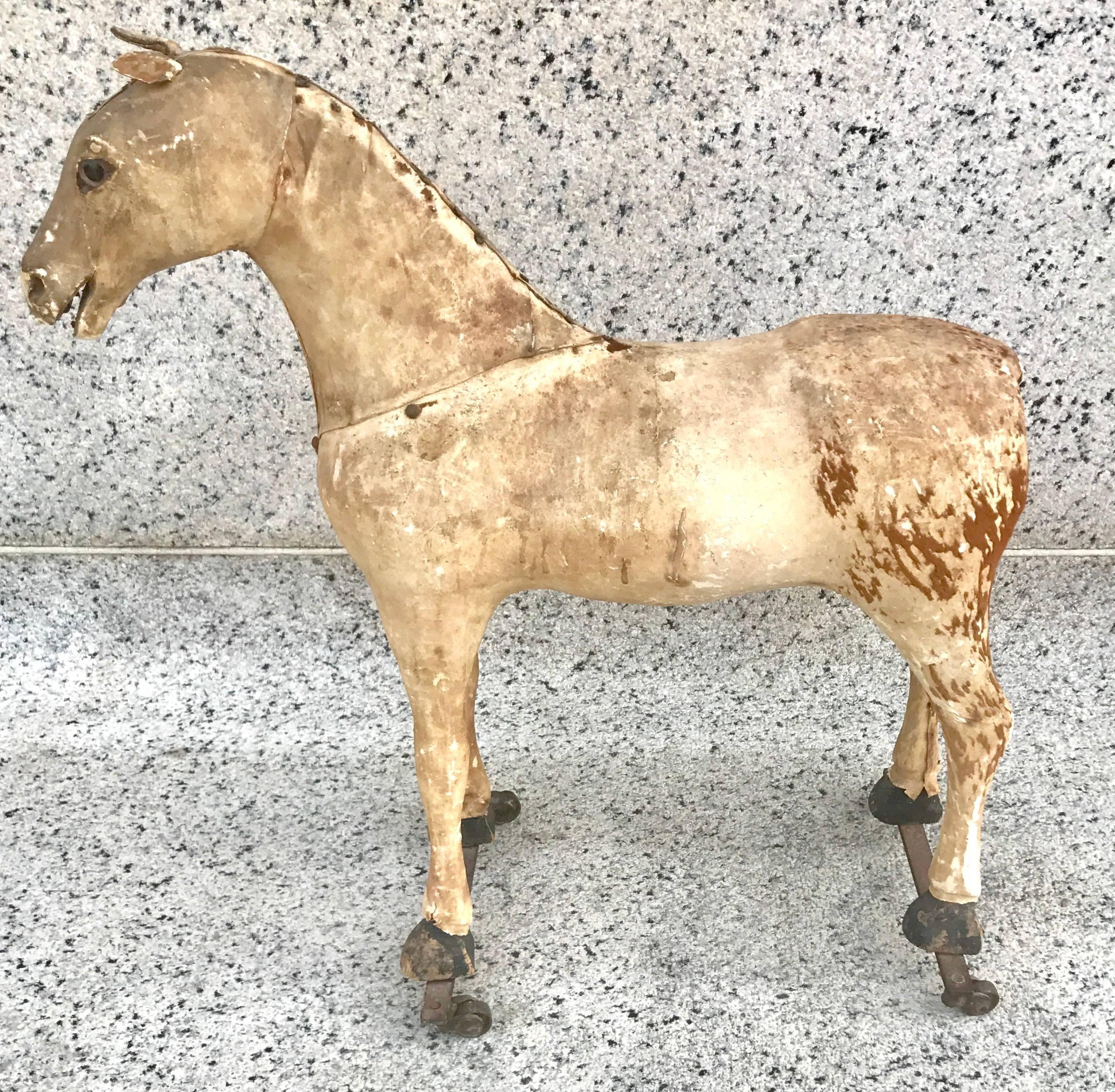 Wonderful large sculptural hide covered child's riding horse, circa 1869, American. Great original patinated surface, and iron wheels. A wonderful example of an early American Folk Art sculpture!