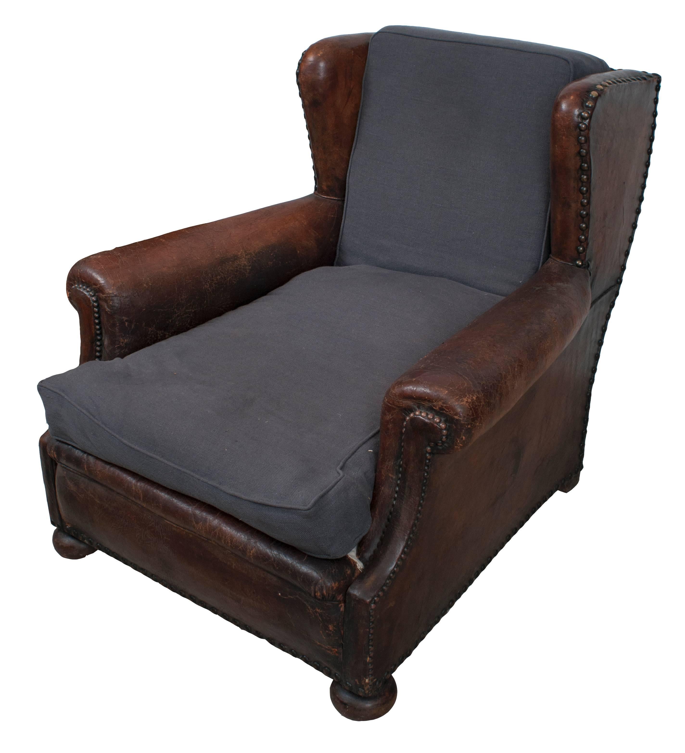 A pair of brown leather and blue linen seat and back cushions club chairs.