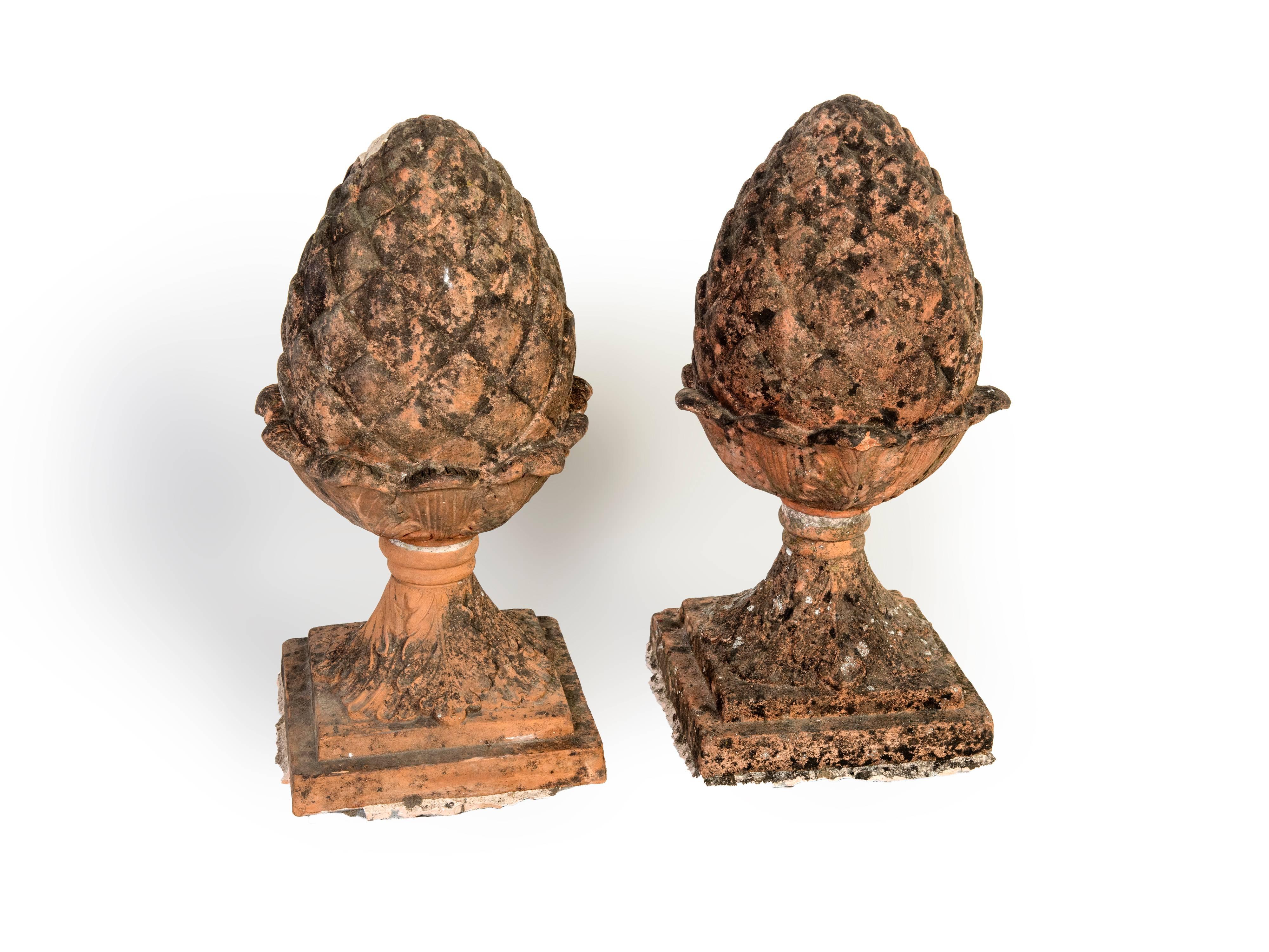 A pair of red terra cotta pineapple garden finials. The patina on these is quite spectacular.