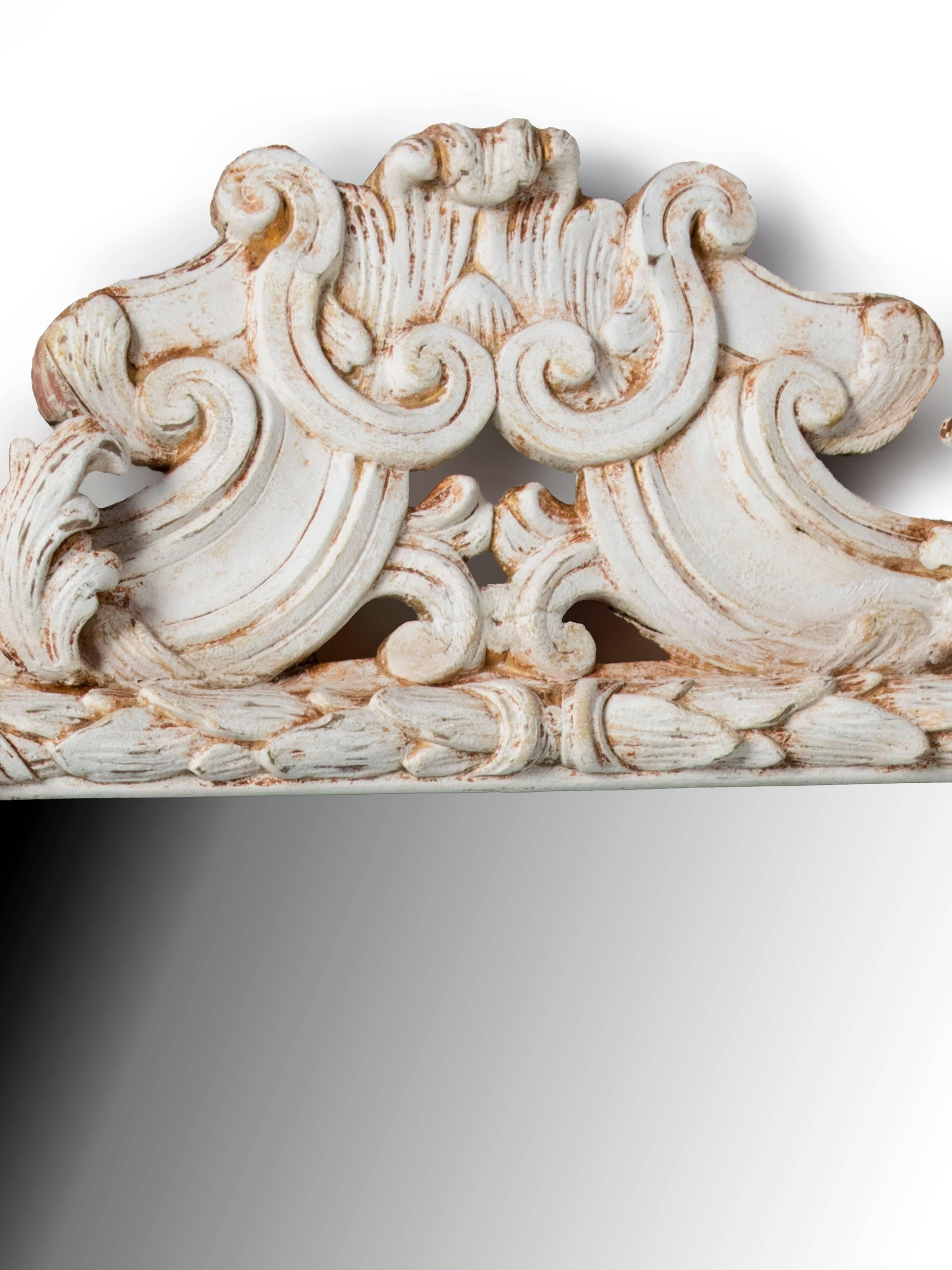 A white painted and carved wood Rococo mirror.