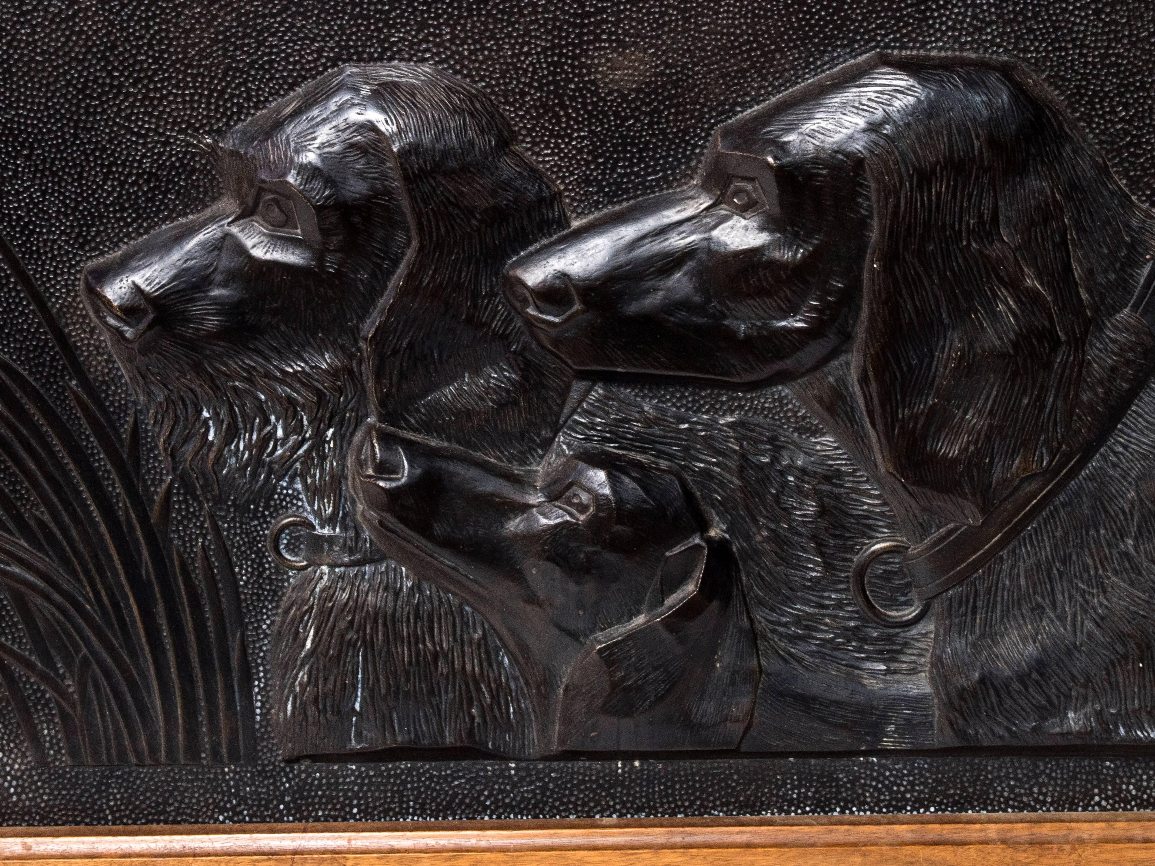 A black painted resin panel of a hunting dogs busts.