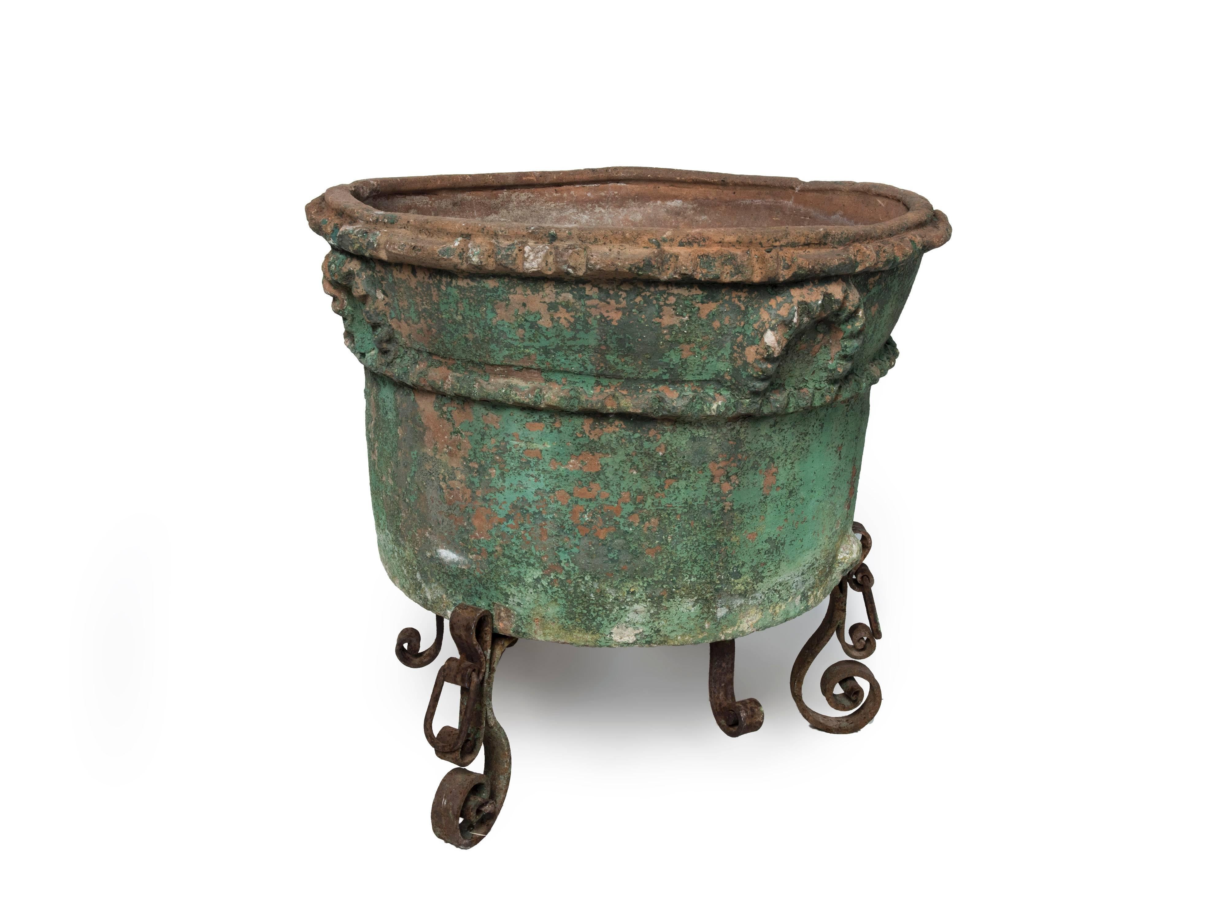 Large painted terra cotta planter with a wrought iron stand.
