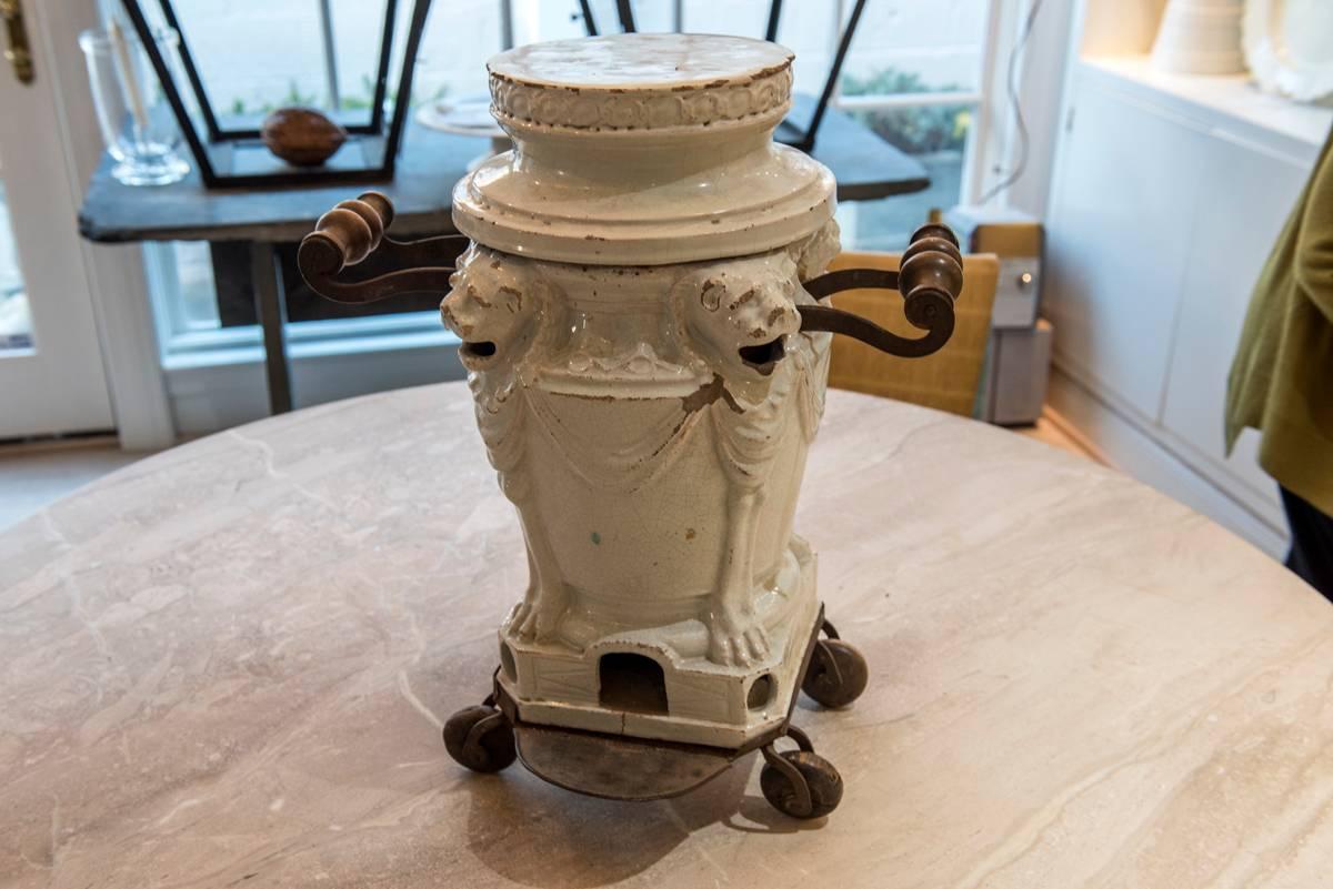 A white faience neoclassical brasero, with coal basket insert and original wooden wheels. Standing lion decoration. All original.