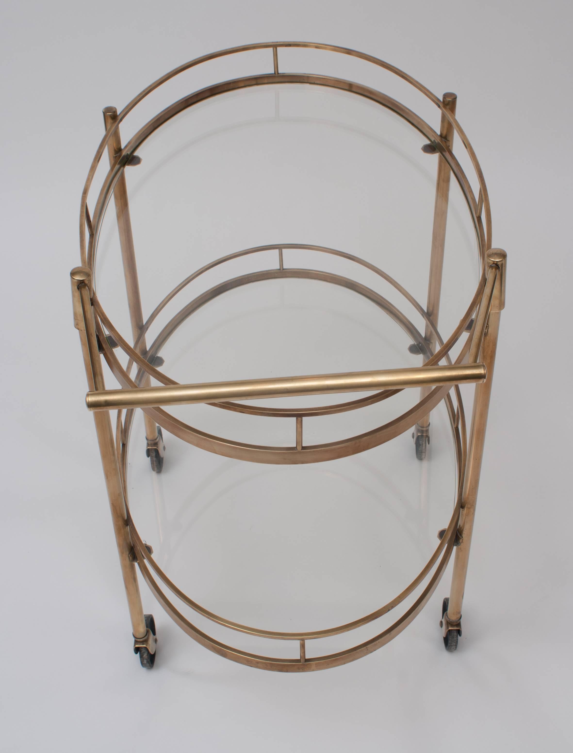 Oval with brass frame and gallery. Two tiers with inset glass and original wheels.