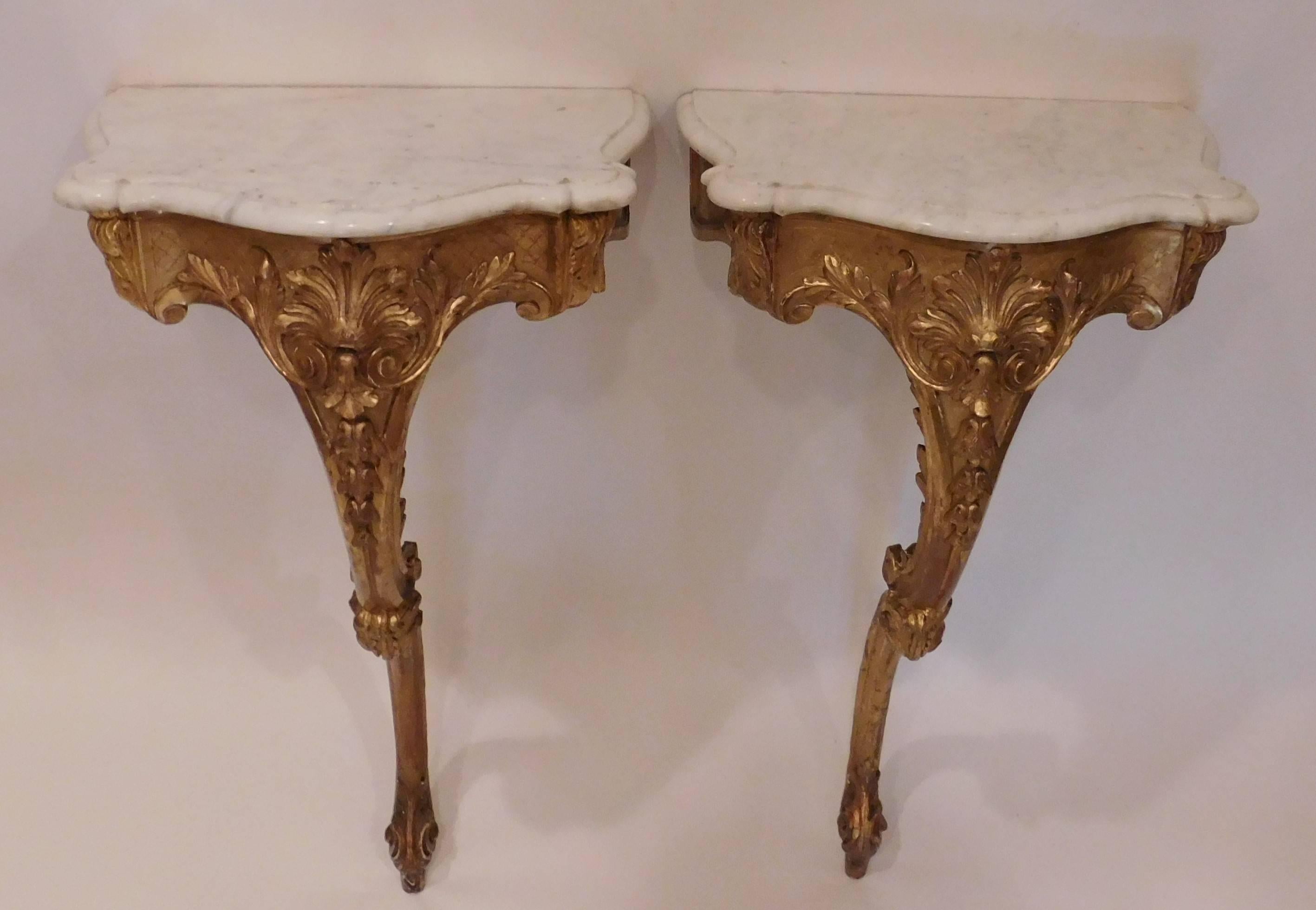 Gold leaf and gilt on gesso on wood with attached marble tops, wall-mounted with single leg, hand-carved, made in either Italy or France.