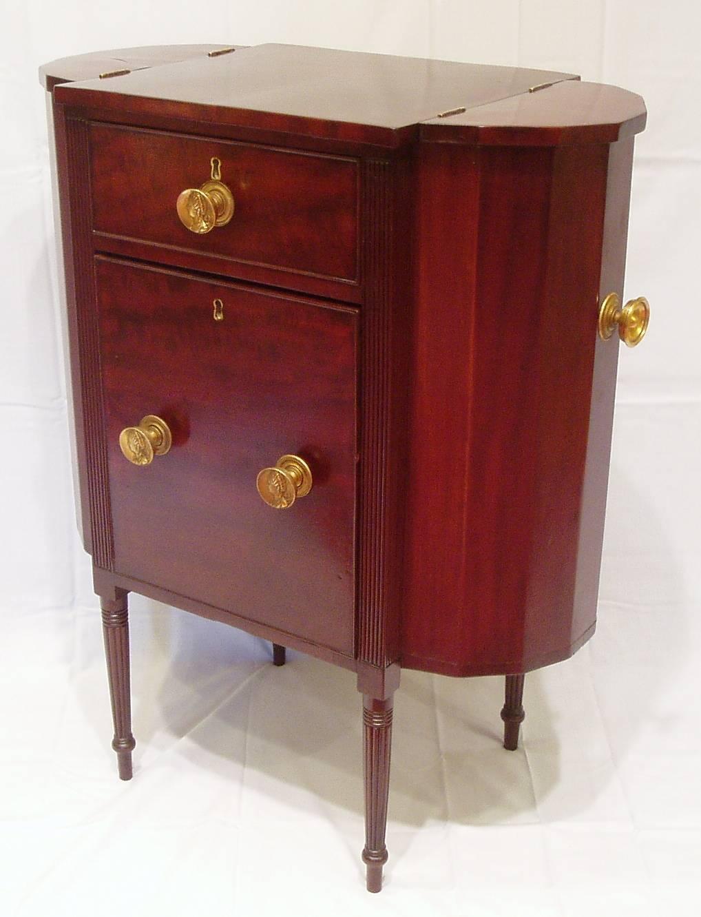 French polished mahogany and mahogany veneer with pine secondary wood old brasses with profile of Queen Charlotte, two center graduated drawers and two lift top ends, top drawer has divided interior, finely reeded legs.