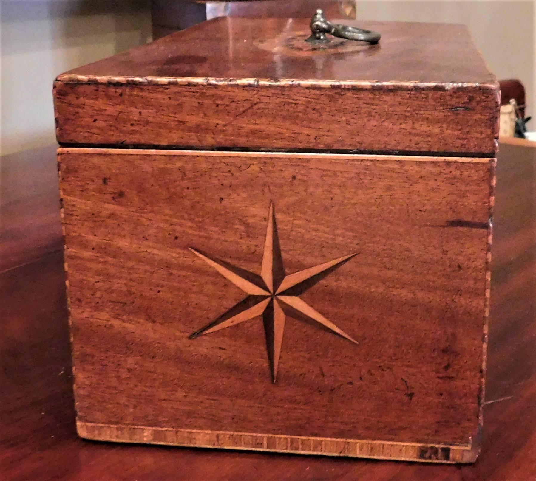 This small Hepplewhite tea caddy has star and eye inlays of harewood and satinwood. It has two compartments with removable zinc boxes, one of which has a lid. The box also has a key and an original brass pull on top. The lid is lined with wool baize.