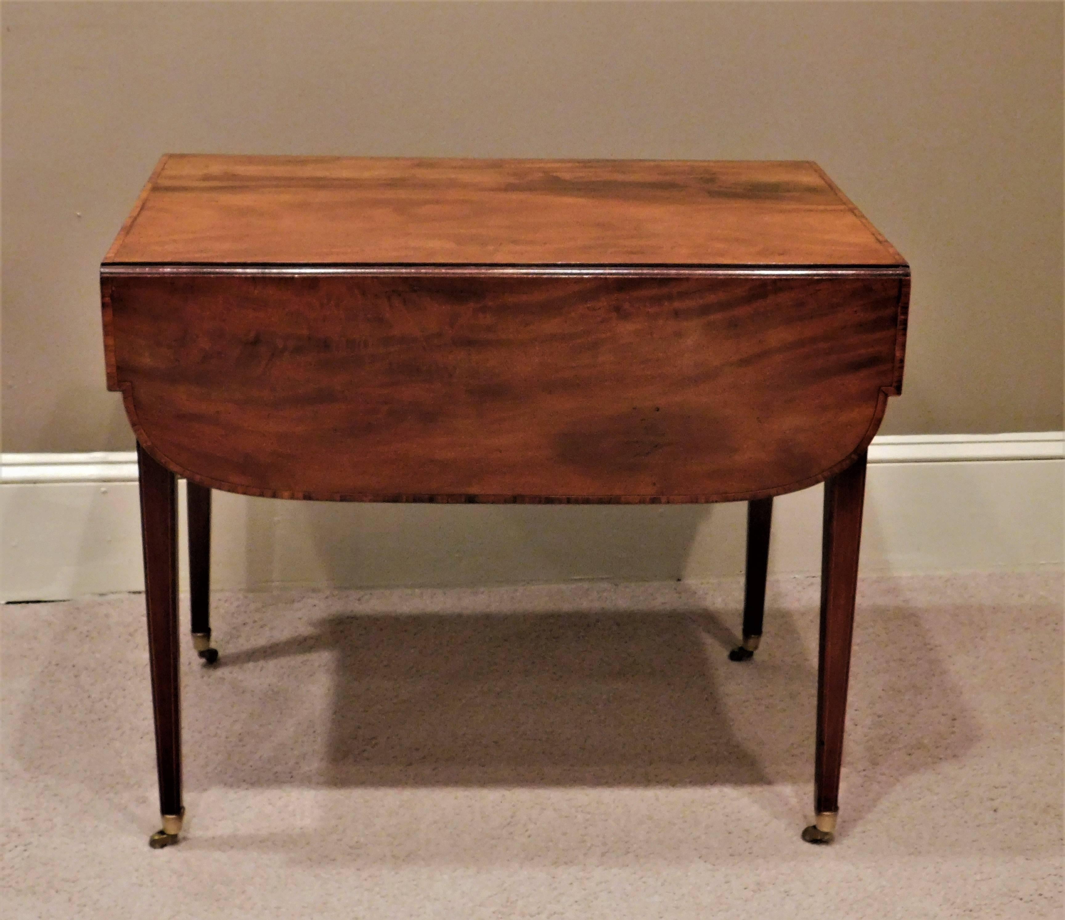 Highly figured plum pudding mahogany with birch and holly inlay. Top is cross-banded in mahogany. Oval and string inlay, tapered legs shaped skirt. One drawer and one faux drawer. With leaves up the width is 38.75
