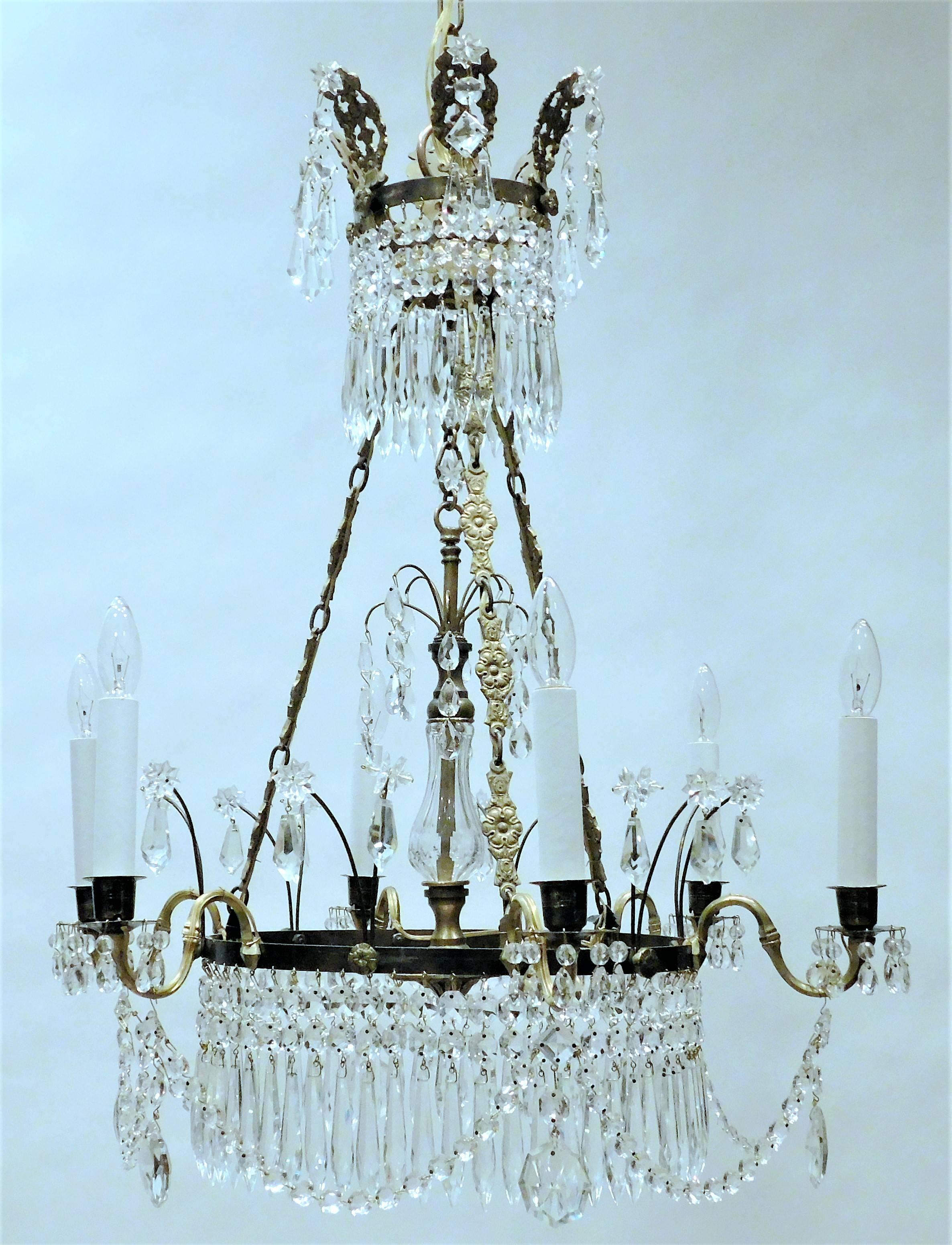 This fixture has 2 concentric rows of hanging icicle lead crystal prisms with hand-wrought brass and gilt brass. Festoons draped between each arm.  Free-hanging pendant in center. Copy of an early 19th century candle fixture.  Hanging hardware,