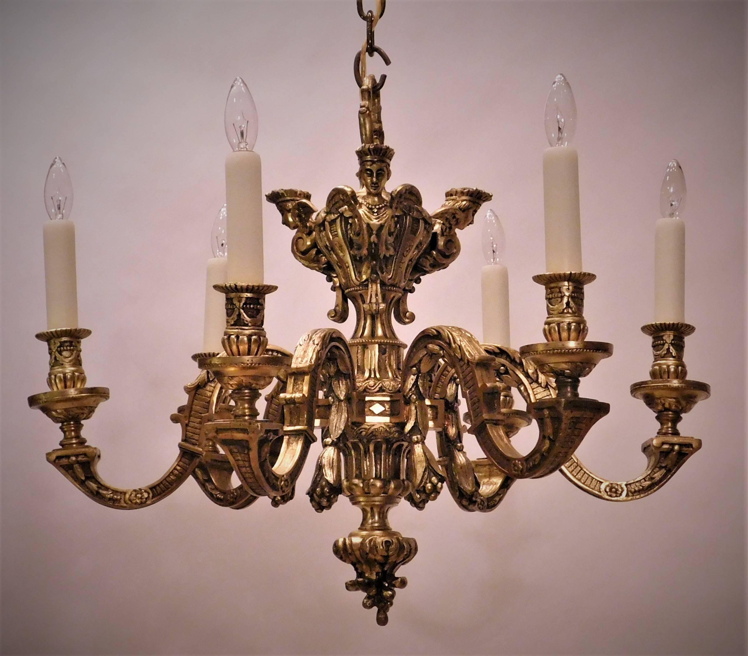 This Baroque style chandelier is hand cast guilt bronze which with age has acquired a beautiful patina. The castings are very intricate. including three female angels' heads. Includes ceiling cap, hanging hardware and one foot of chain (which brings