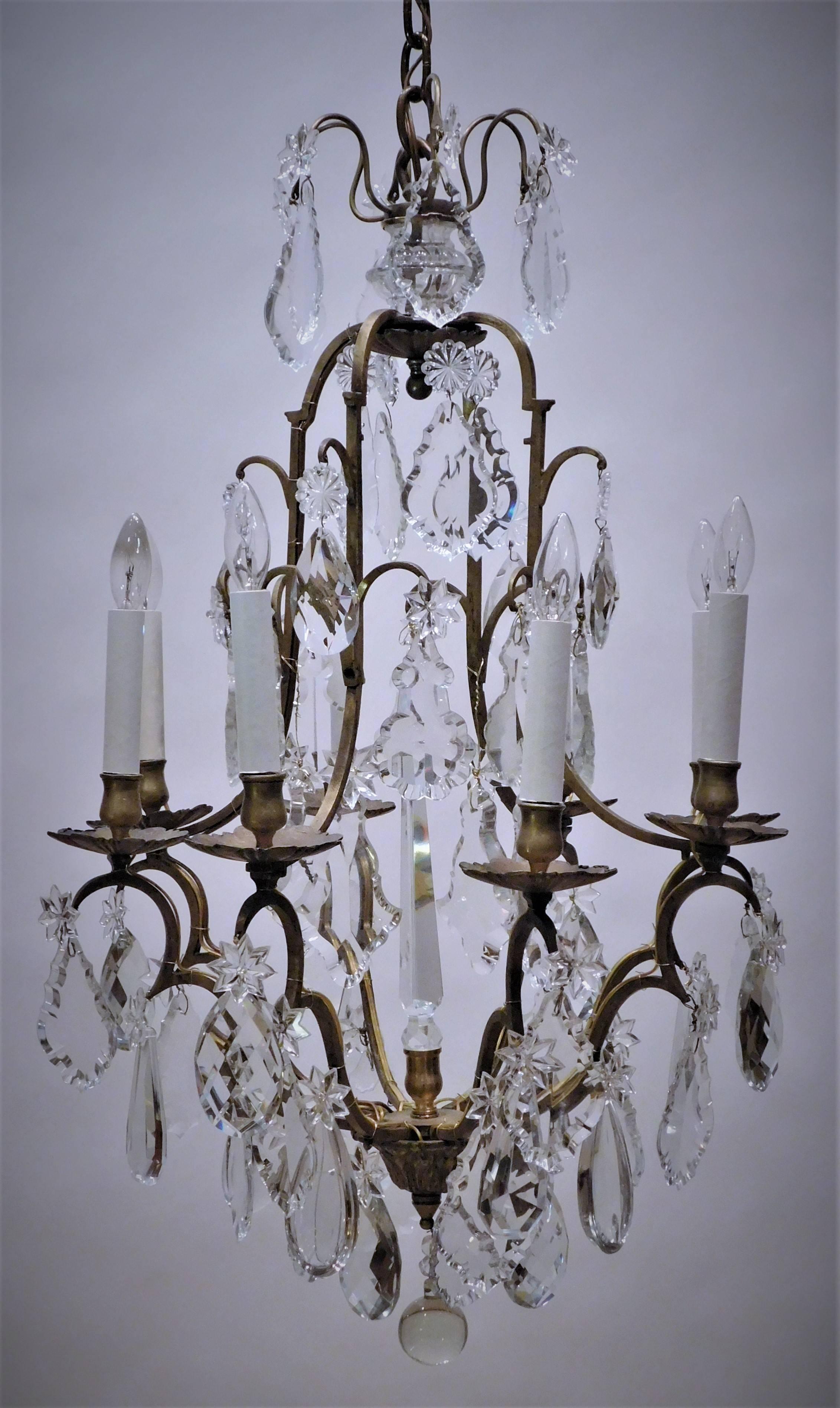 This fixture was originally a candle chandelier and was electrified in the 1940's in France. The bronze frame is hand crafted and the lead crystal includes Baccarat cut prisms. Ceiling cap, hanging hardware, and one foot of chain included.