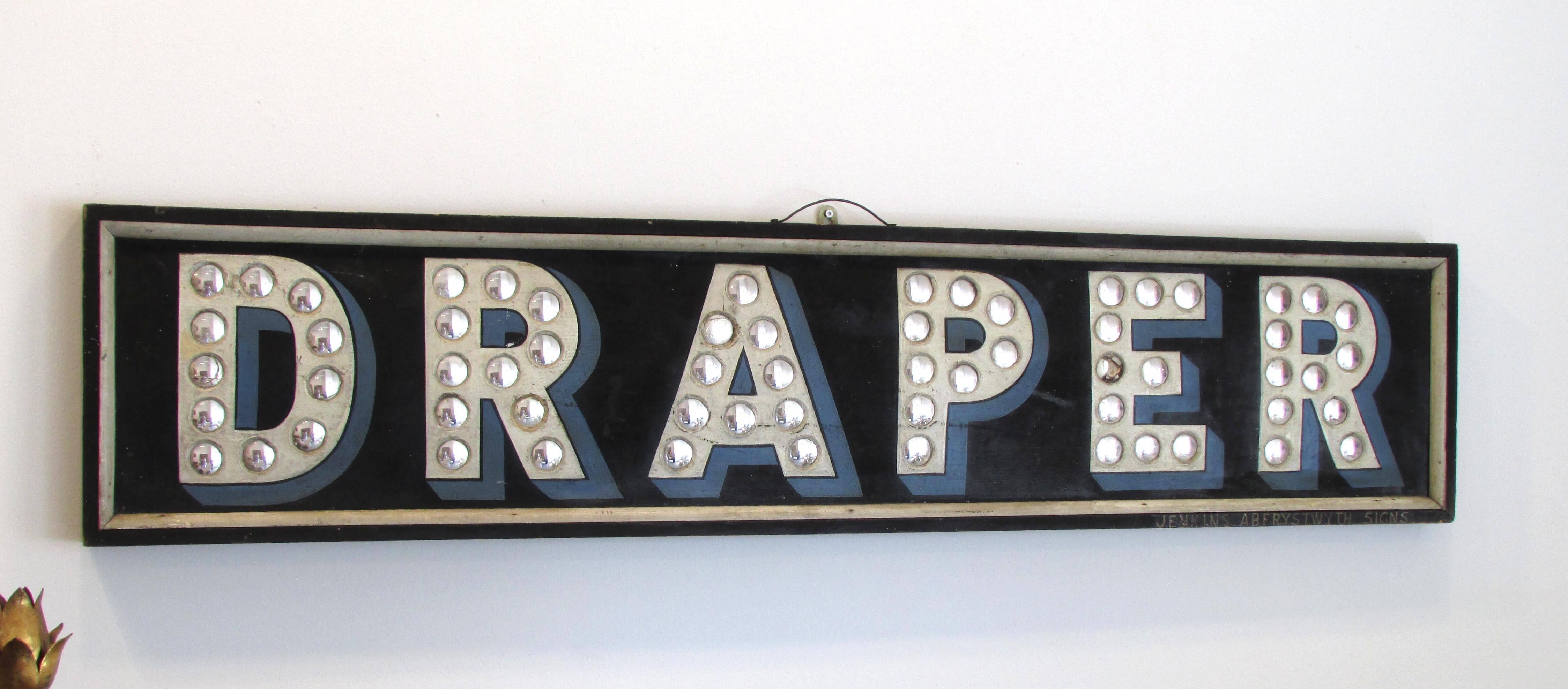 Painted wooden trade sign with small inset convex mirrors spelling out 