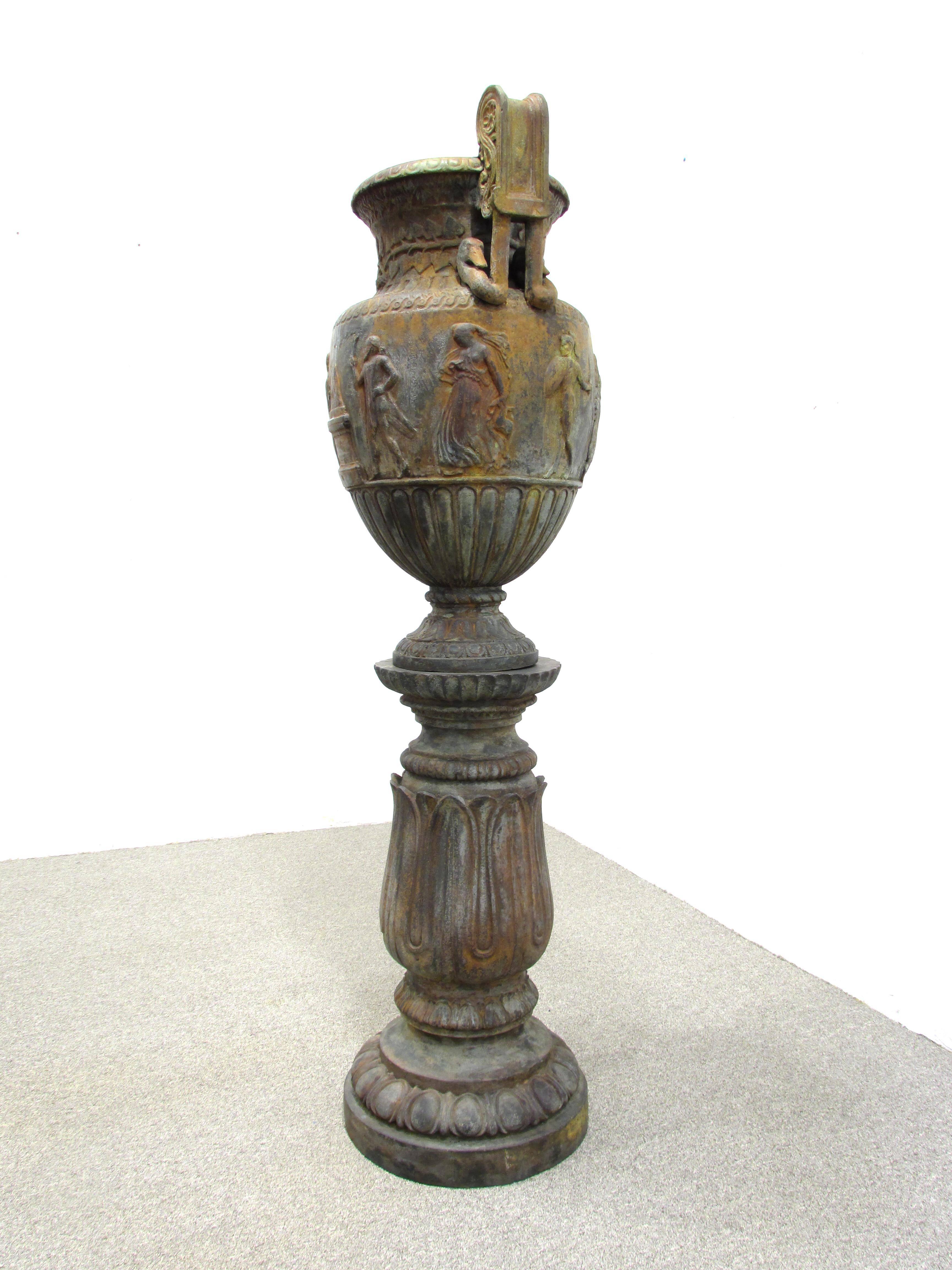 Large bronze urn in the neoclassical style the main body with musicians and hunting figures over lotus leaf base and swan neck and scroll handles.