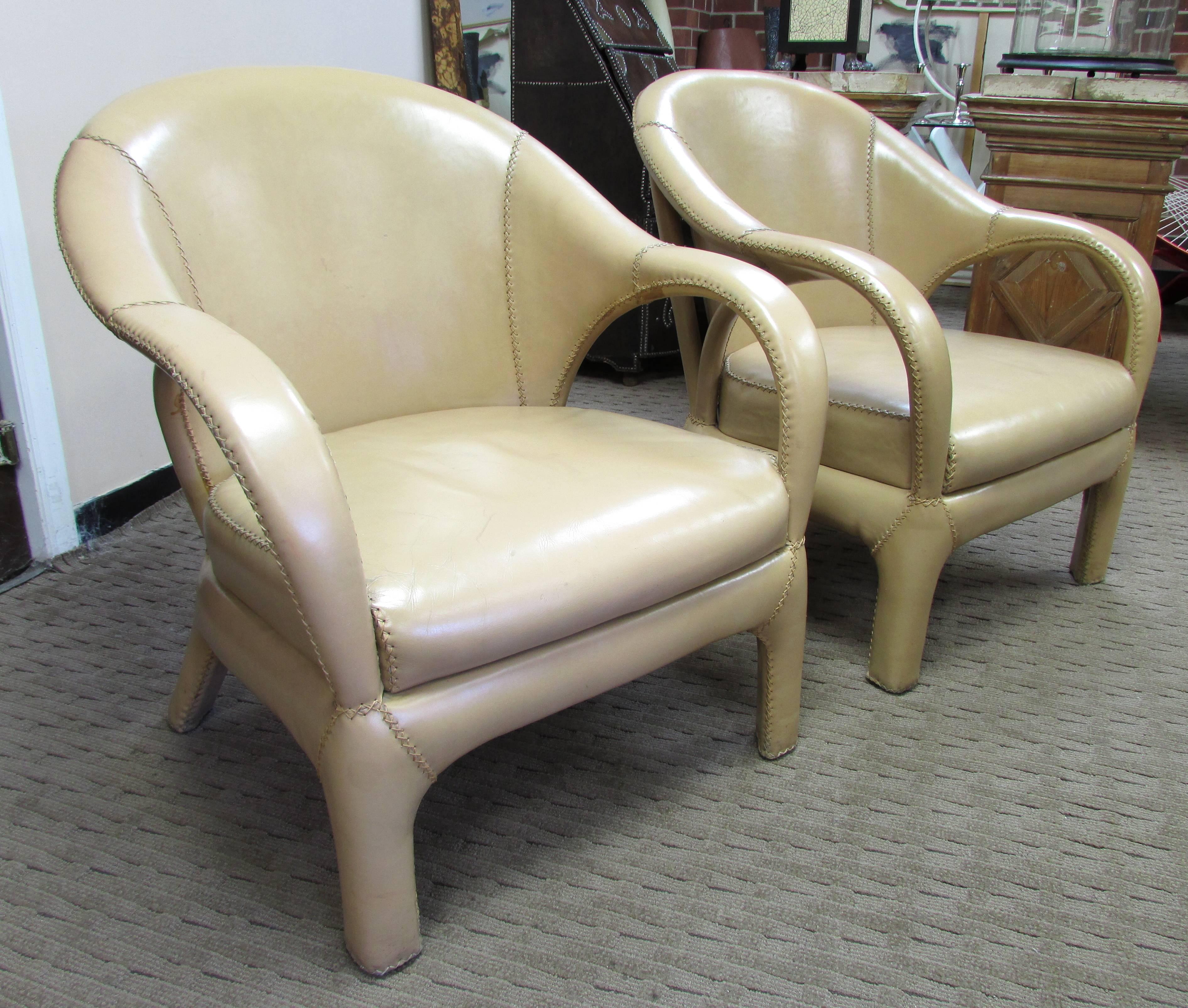 Pair of tan leather tub chairs with hand stitching throughout including frame
