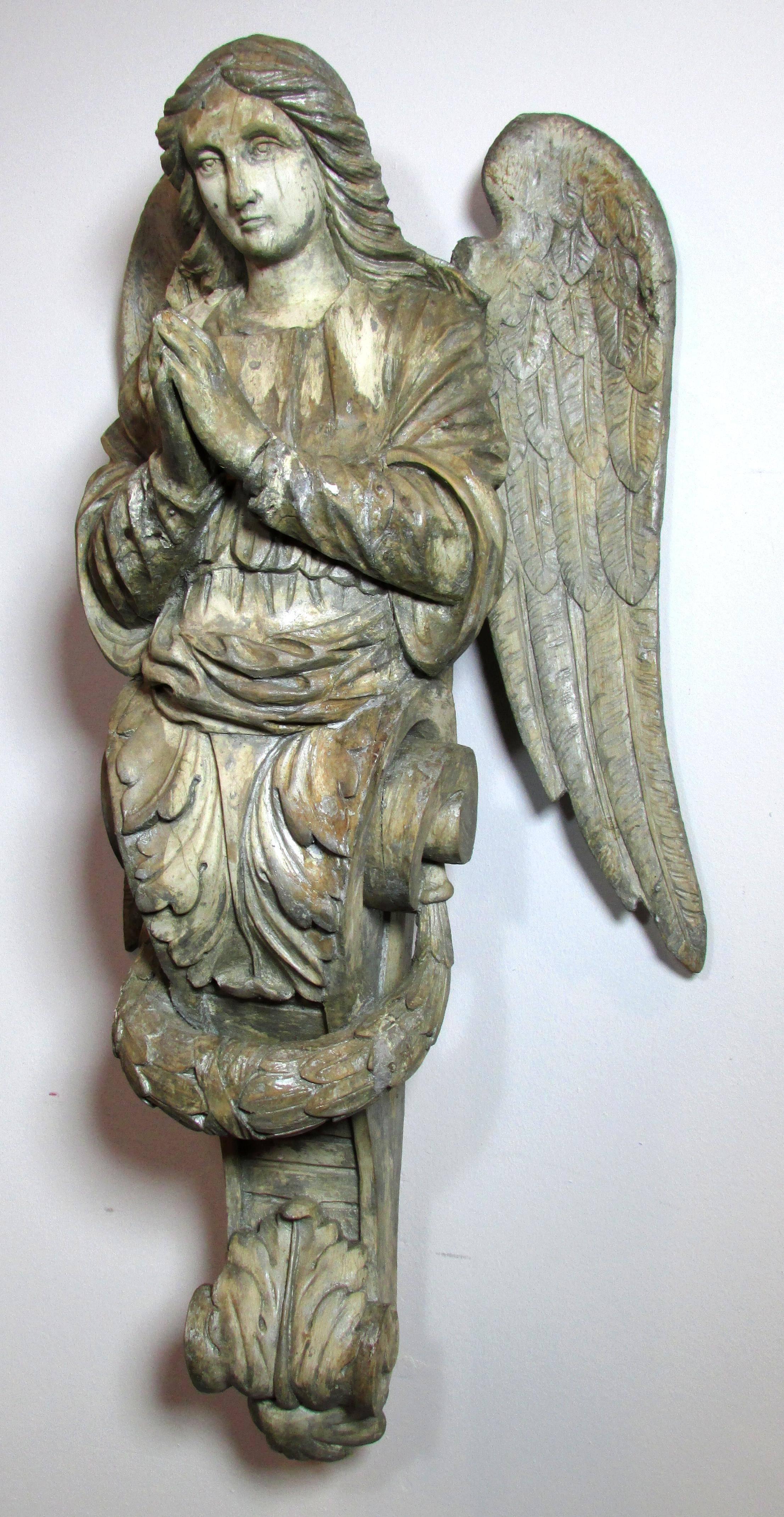 Carved wooden architectural element of an angel painted with gesso and remnants of silver paint.
