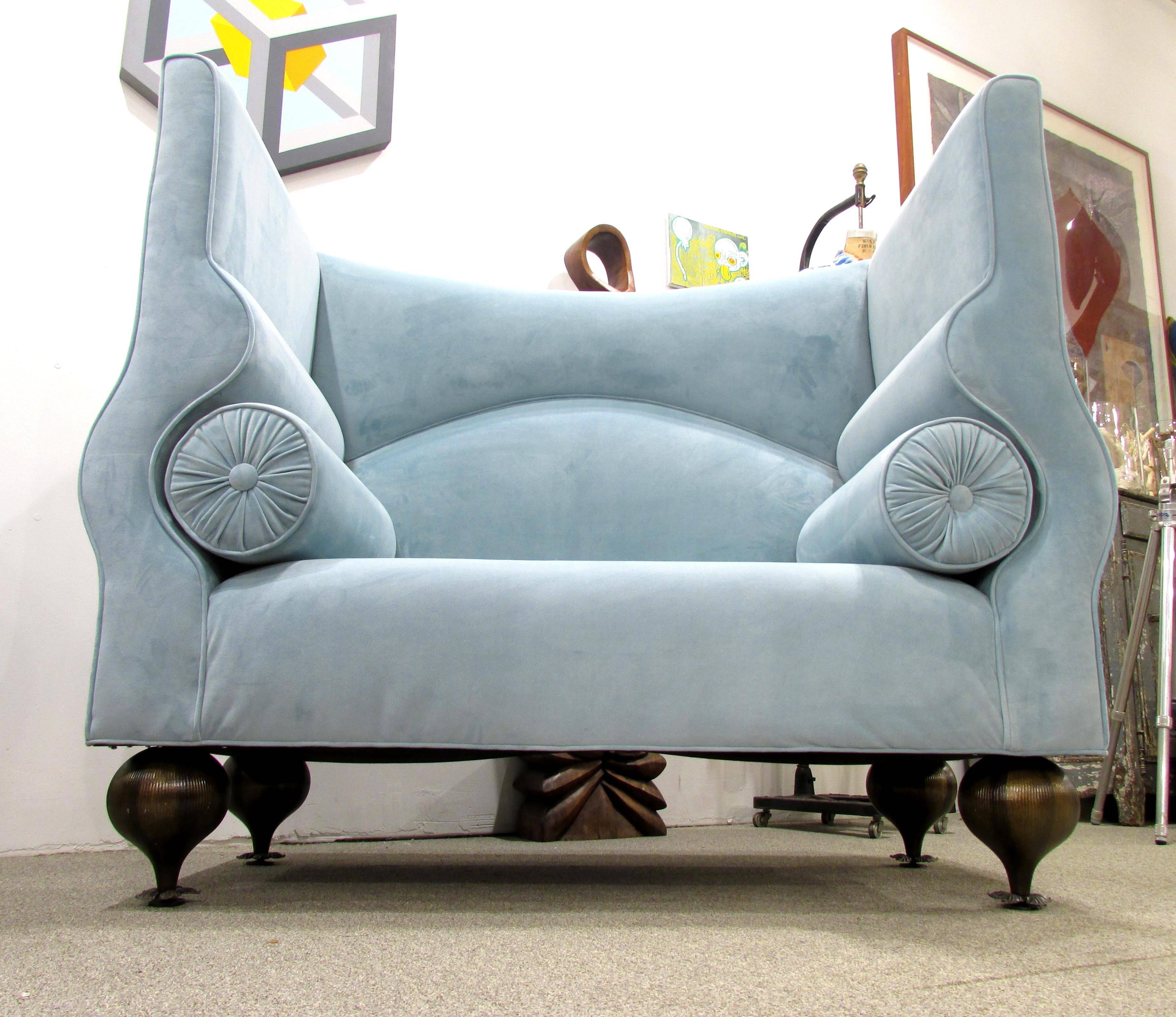 Whimsical high back settee sofa with wonderful curves upholstered in light blue faux suede with inset bolster pillows and metal inverted onion feet