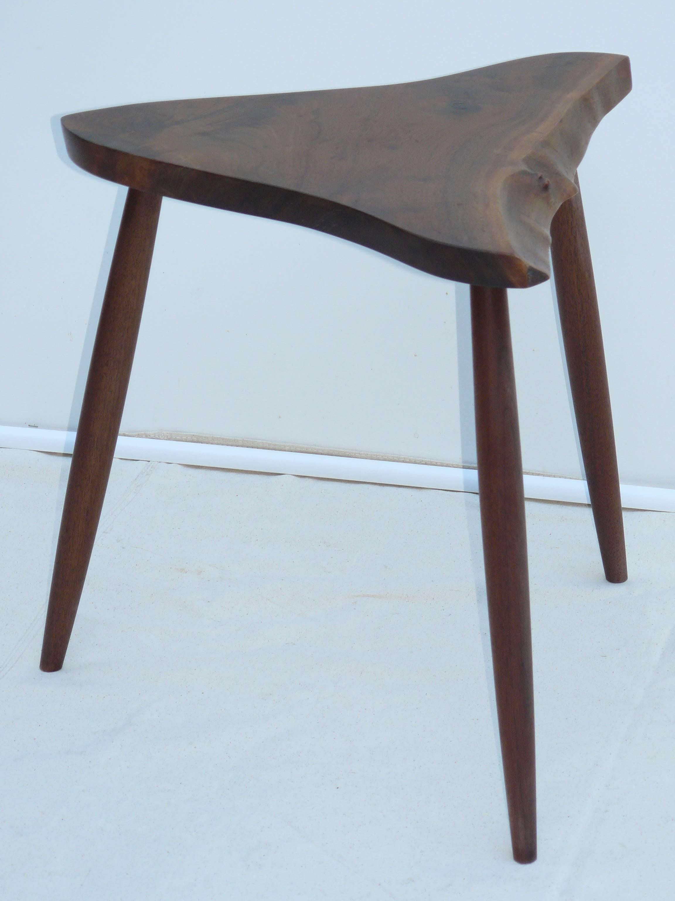 George Nakashima Wepman table. 1980s production, comprised of three spindle legs and a triangular walnut slab, one side retaining the tree's original free-form edge. At 21