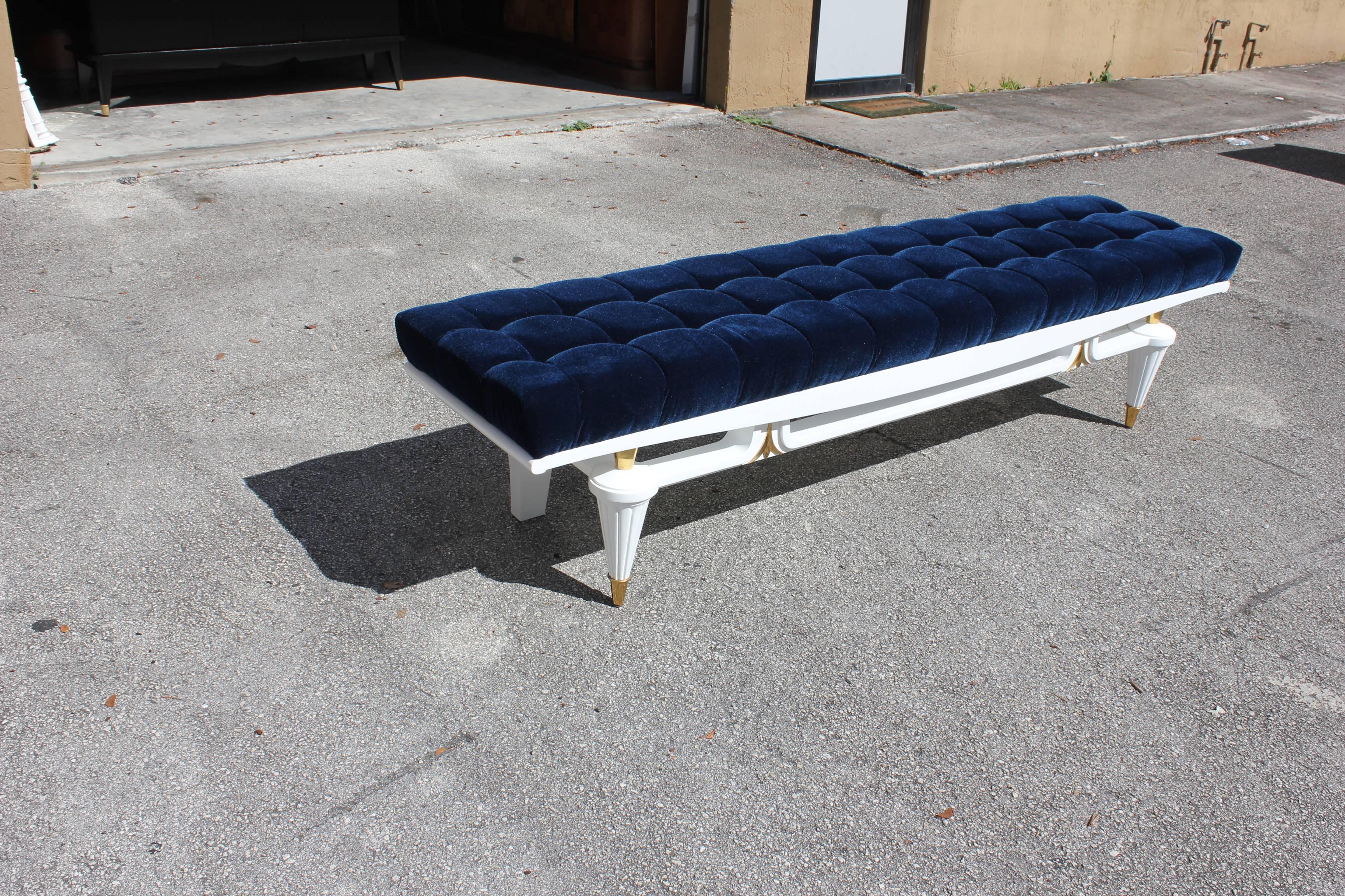 Monumental French Art Deco snow white lacquered mahogany sitting bench with beautiful hardware, circa 1940s. Newly upholstered in a very high textile velvet royal blue. Newly refinished. White lacquer legs with brass caps. We bought this beautiful