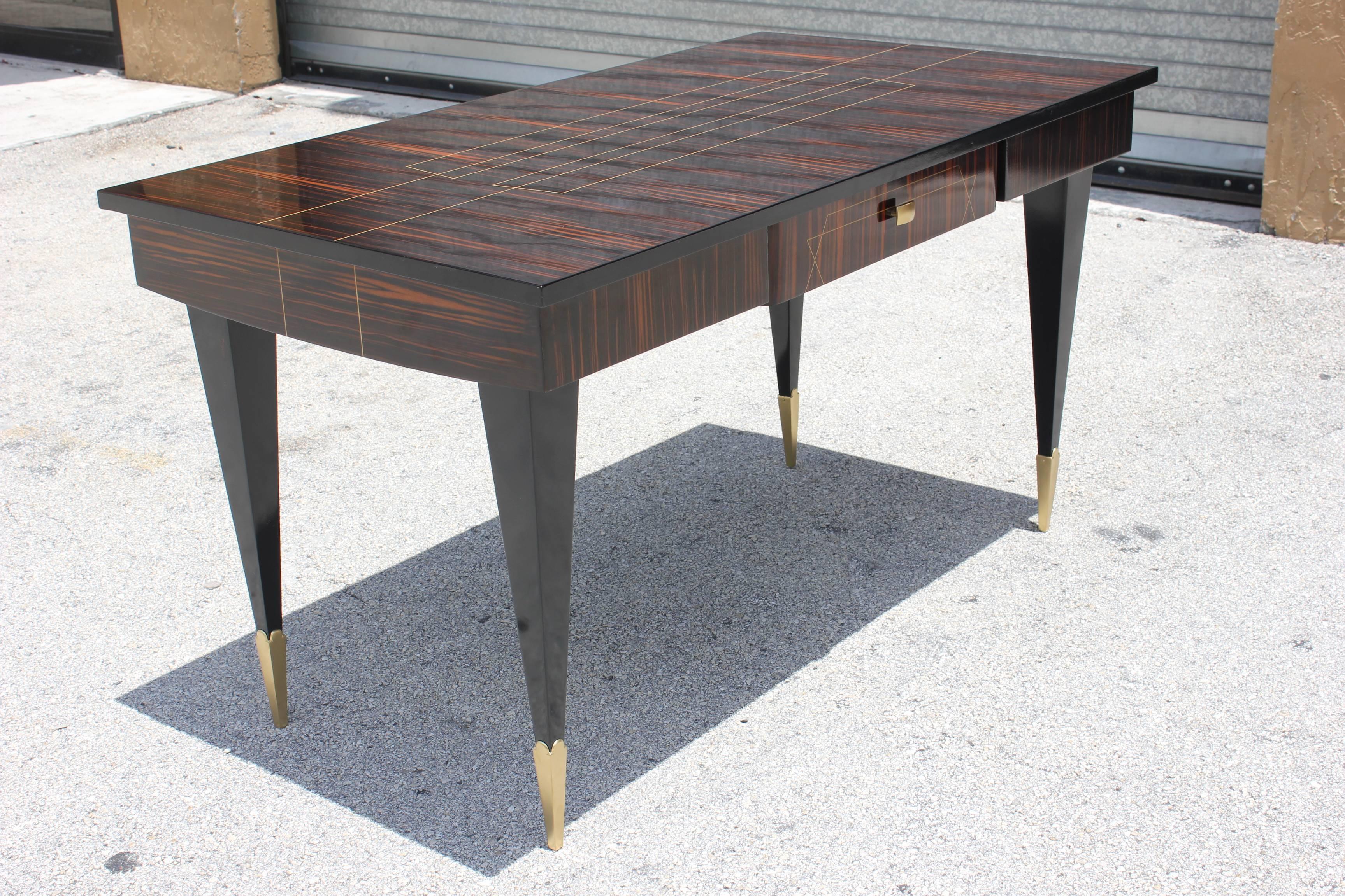 A stunning French Art Deco exotic Macassar ebony writing desk. Gorgeous wood! Inlay on the top and desk drawer. Brass accents on the legs and brass toe caps. Black lacquer legs. French estate find.