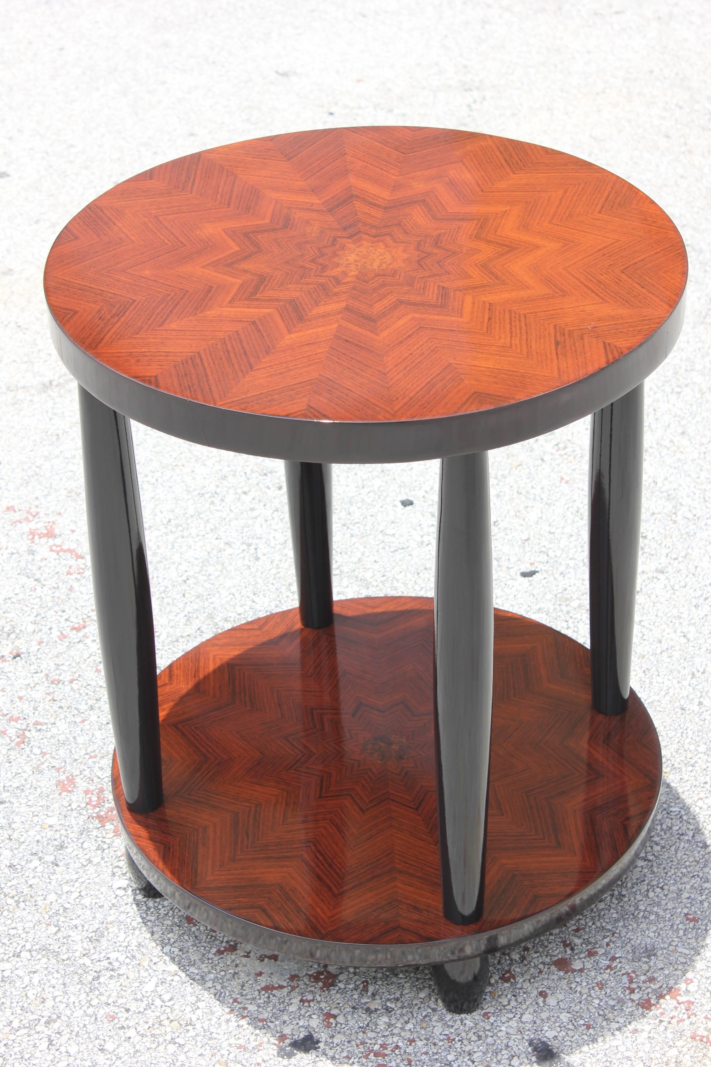 A beautiful French Art Deco two-tiered palisander inlaid starburst accent table, circa 1940s. Black lacquer supports. The inlay is a work of art.