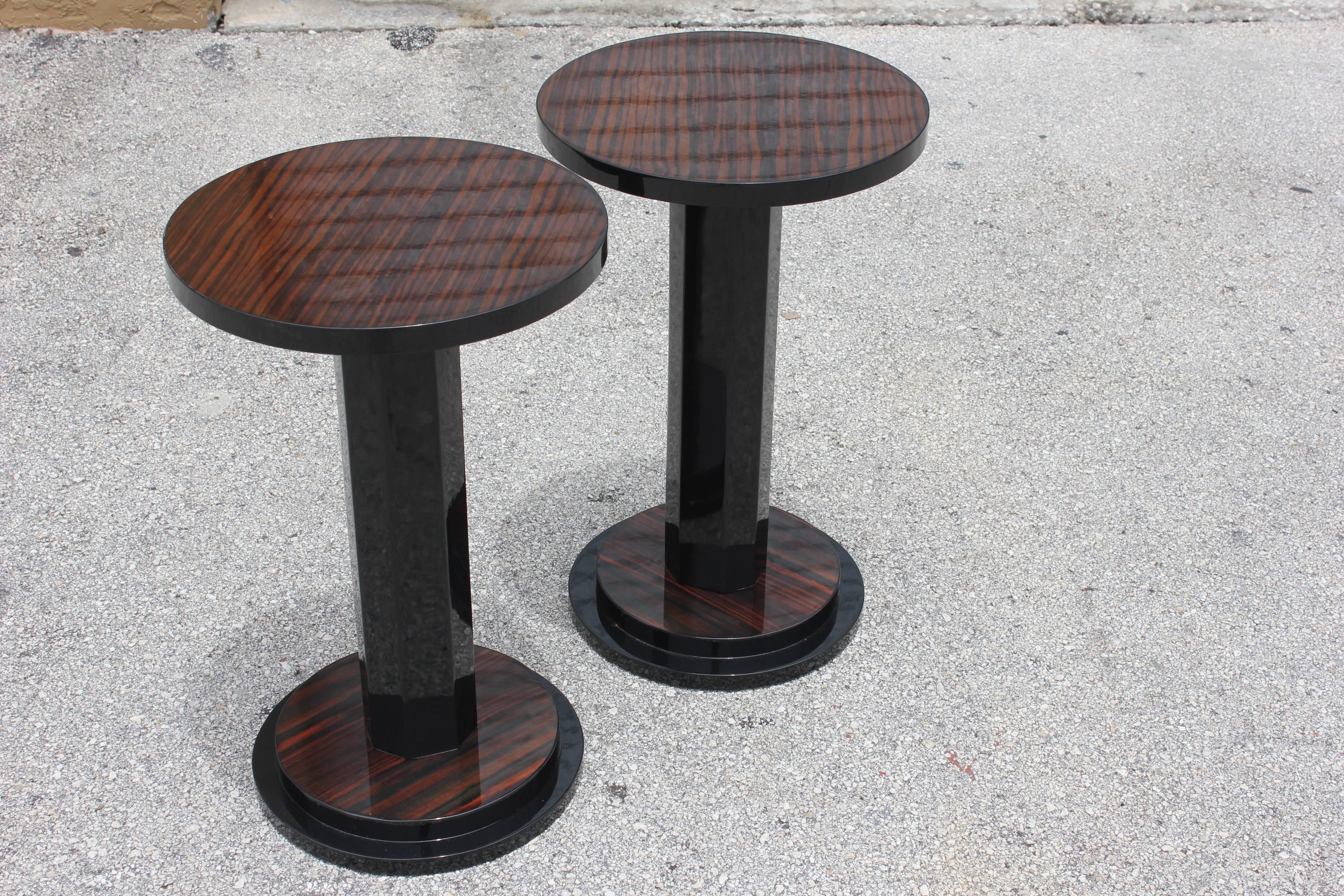 A pair of French Art Deco exotic Macassar ebony end tables, circa 1940s. Black lacquered center columns and accents. Two-tiered bases. Newly refinished and lacquered. We acquired five pairs of these tables from the lounge of a French hotel. There