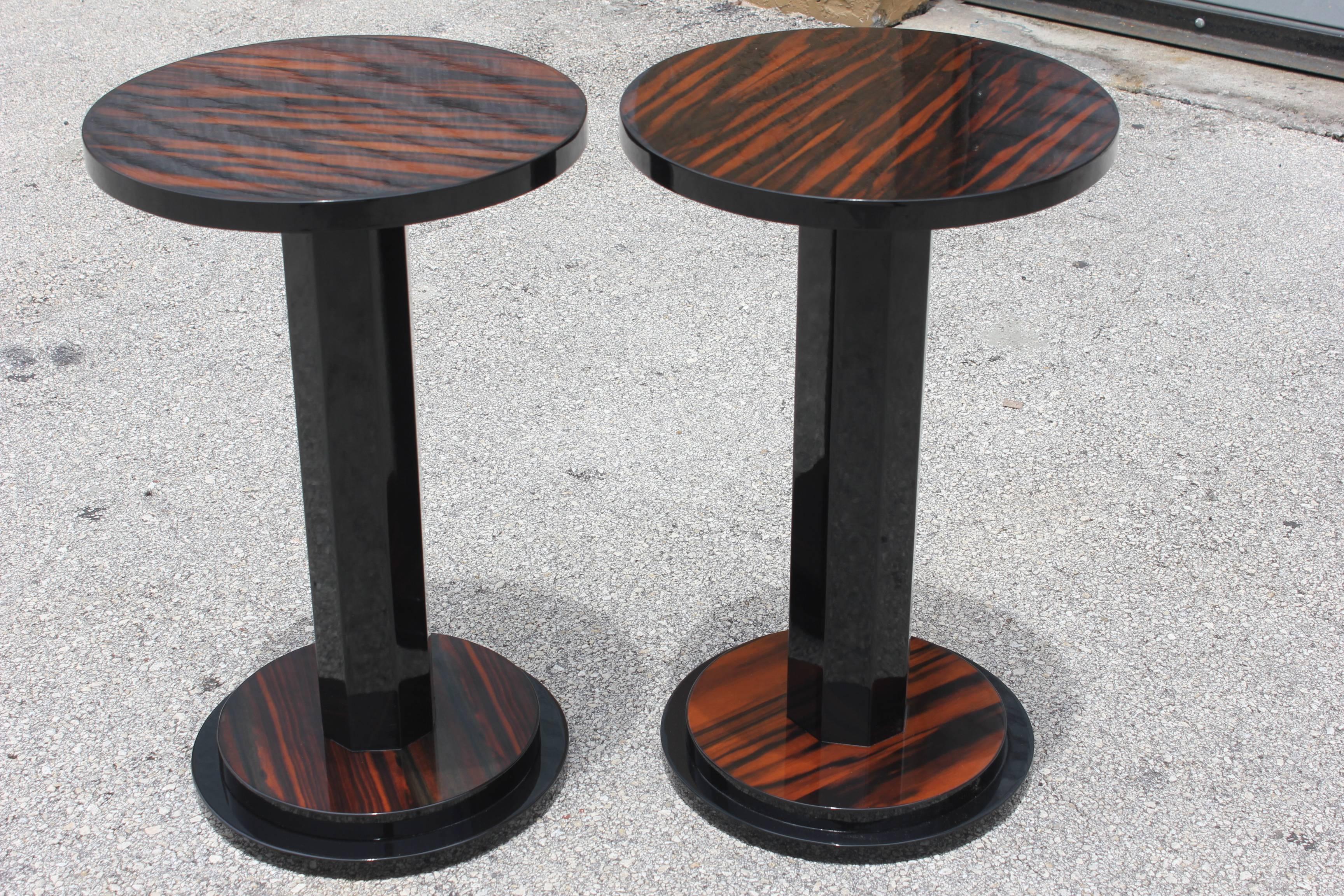 A pair of French Art Deco exotic Macassar ebony end tables, circa 1940s. Black lacquer center column and accents. Two-tier base. Recently refinished and lacquered. We acquired five pairs of these tables from a French hotel. There are slight