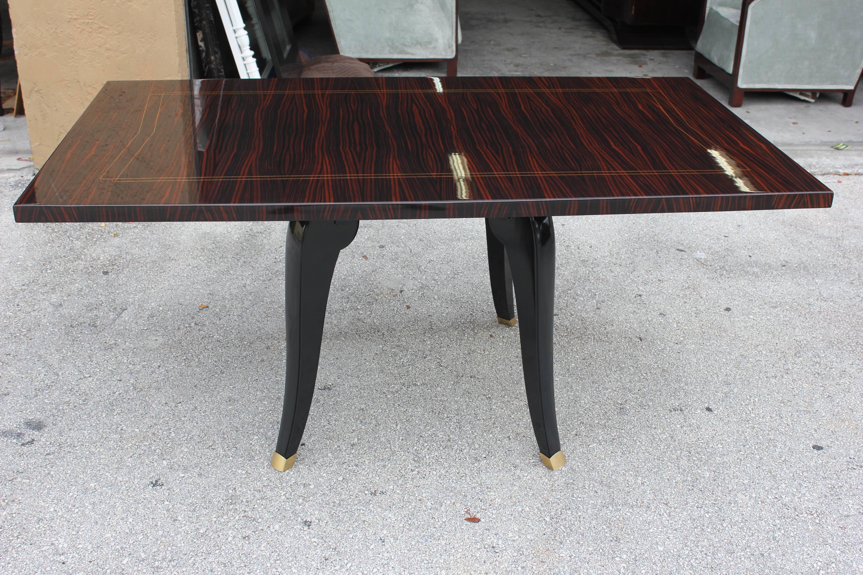 A French Art Deco exotic Macassar ebony sabre leg dining table, circa 1940s. Black lacquer legs. Newly refinished in a lacquer finish. Brass toe caps. This is a spectacular table and was acquired from a French Estate.
