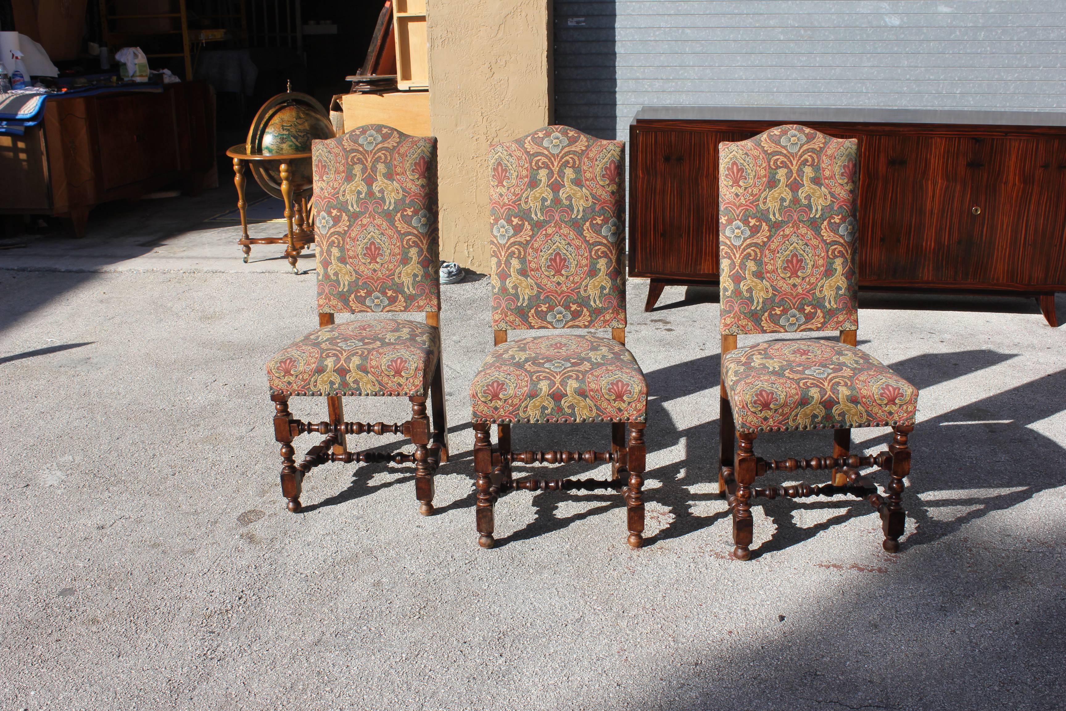 French Louis XIII style dining chairs, set of six. Solid, carved walnut featuring turned front legs and stretchers with straight back legs. Each with chapeau de gendarme back and upholstered with nailhead trim, circa 1880 from Paris, France.