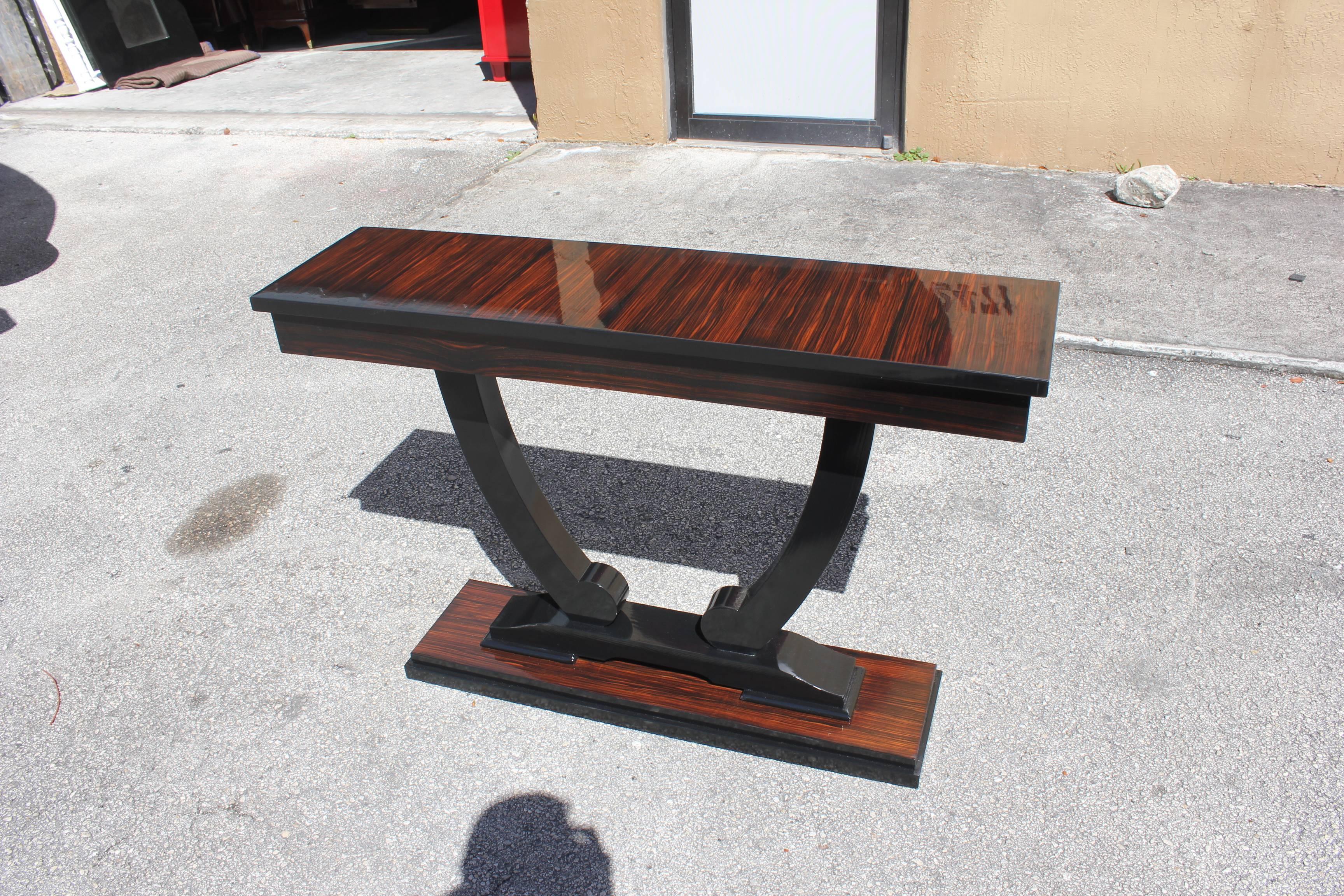 Unique pair of French Art Deco exotic Macassar ebony console tables, circa 1940s. Beautiful Macassar ebony with black lacquer base, High gloss lacquer finish in both side, that rest on makes it ideal for use as a bedside table. A fine example of