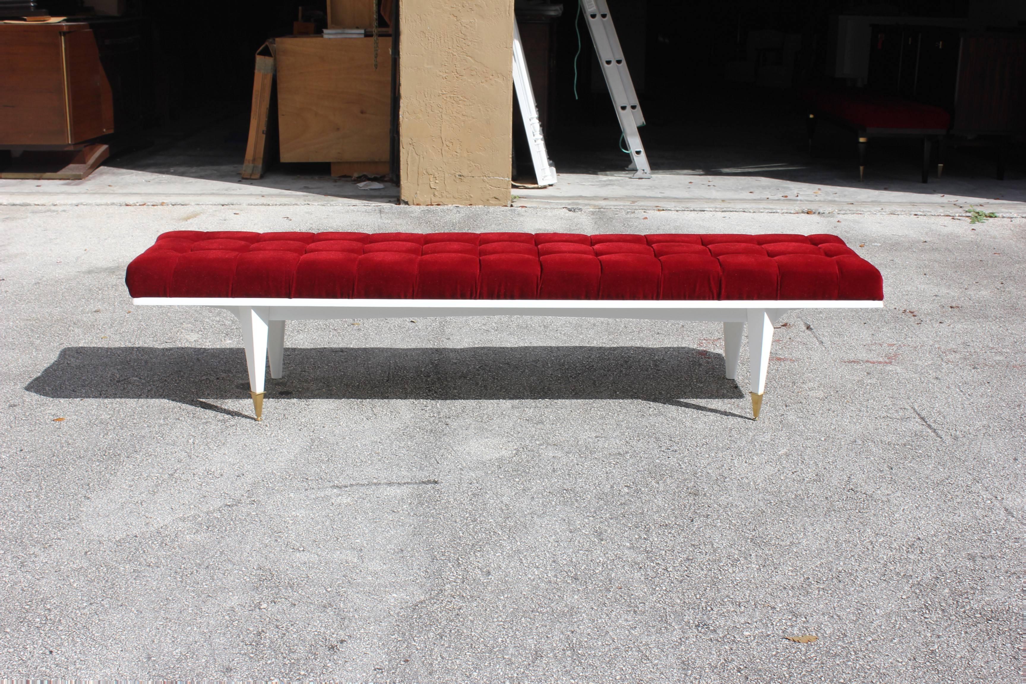 A long French Art Deco snow white lacquered mahogany sitting bench, circa 1940s. Newly upholstered in a very high textile velvet red. Newly refinished. White lacquer legs with brass caps. Size 89.50 W, 20 D, 20 H.