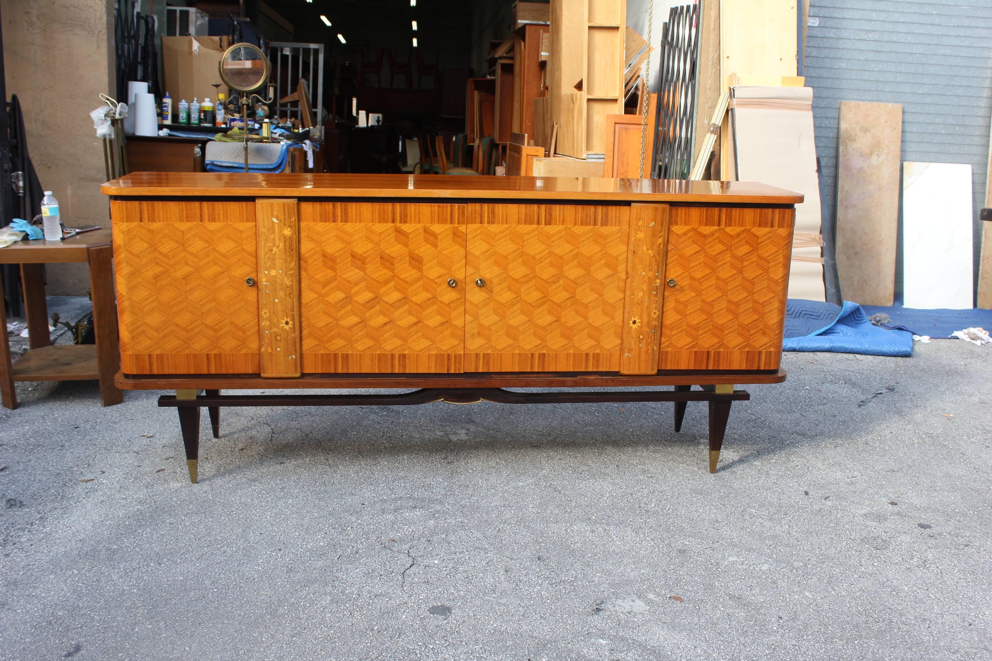 French Art Deco sideboard or buffet in the style of Jules Leleu style. Comprised of light exotic Macassar ebony, with mother-of-pearl and exotic wood inlay. This piece is in very good condition; the piece have four doors with adjustable shelf, circa