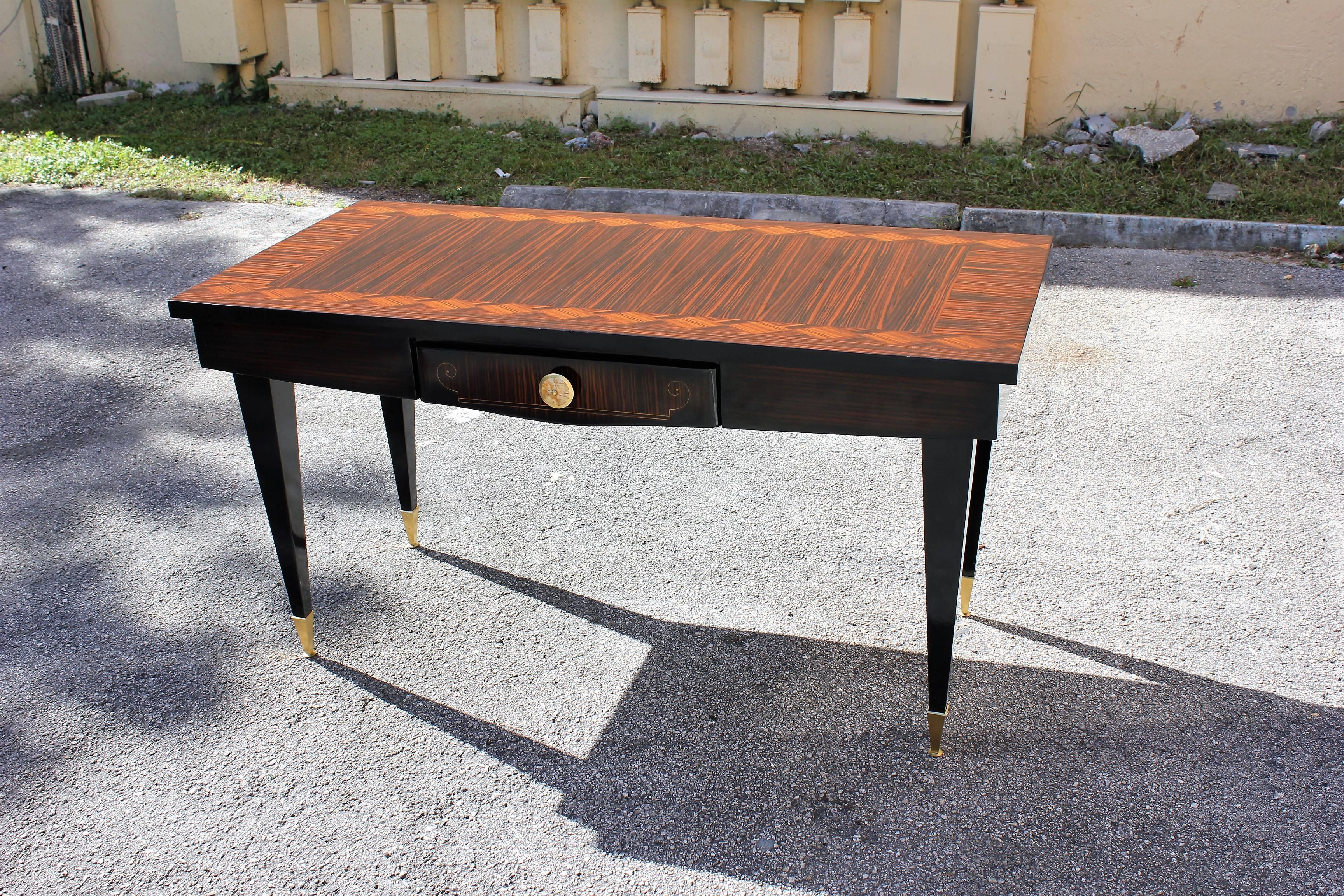 A stunning French Art Deco exotic Macassar ebony writing desk. Parquetry wood! With mother-of-pearl hardware drawer, brass accents on the legs and brass toe caps. Ebony legs. Size. 57 W, 27 D, 30 25 H. We traveled to buy all our pieces in France .We