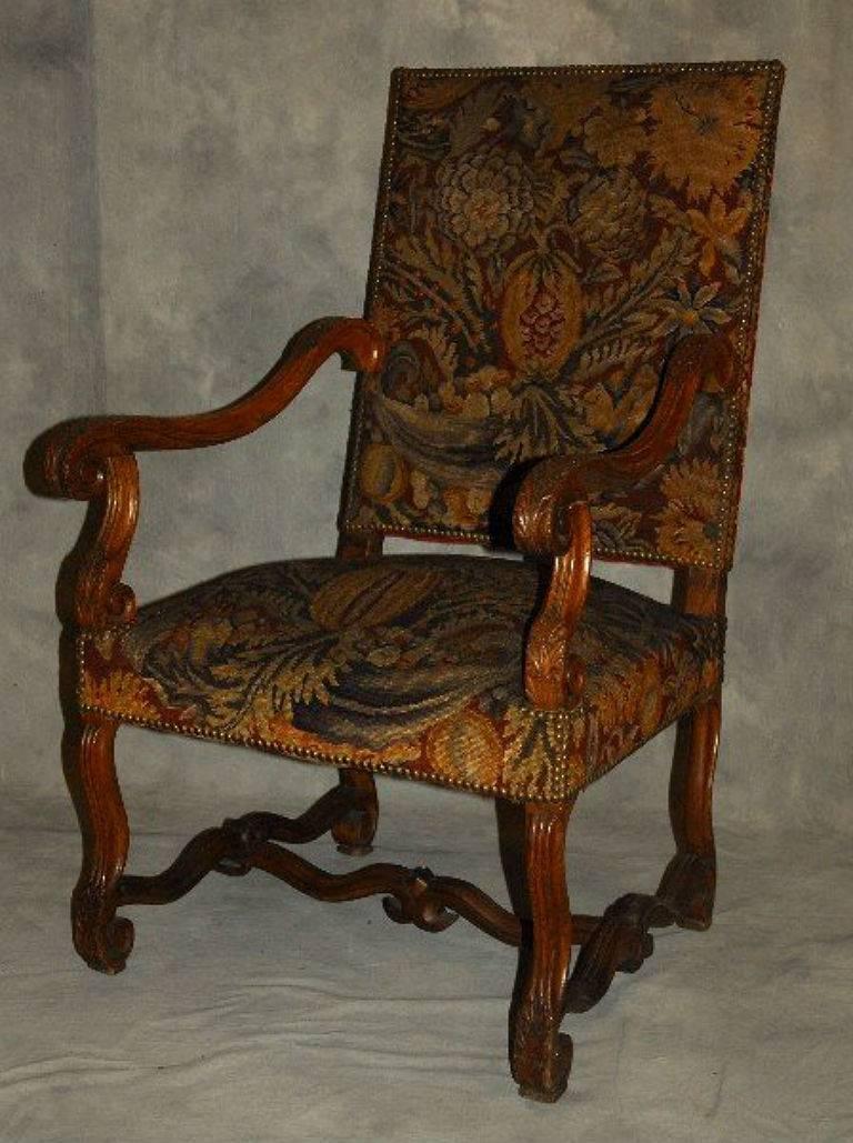 Pair of Louis XIV carved oak needlepoint upholstered open arm chairs. 