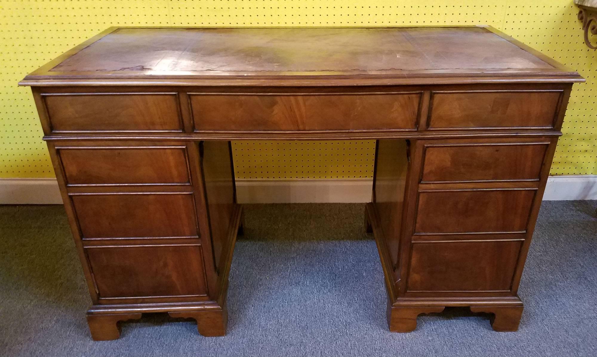 English George III style mahogany double pedestal desk with rectangular inset leather top above a center frieze drawer flanked by eight drawers on bracket feet. Height: 29.75