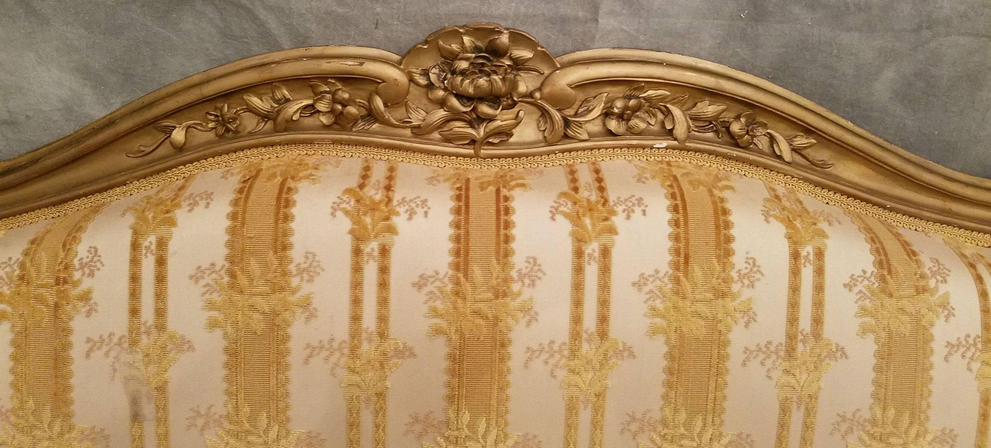 Louis XV style carved and gilded six leg canape with rosette and leaf carved crest and seat rail and carved cabriole legs ending in scroll feet.