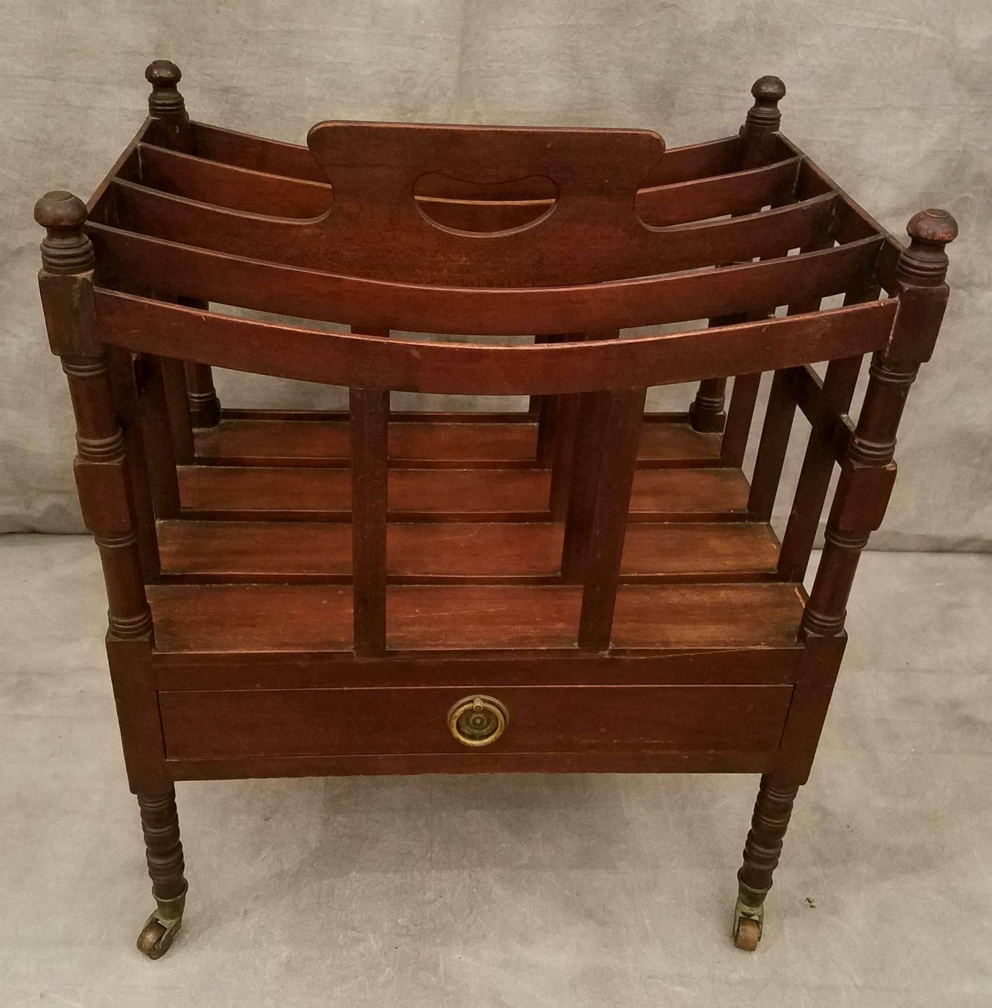 Regency style mahogany four divide canterbury with single frieze drawer on turned legs ending with brass caps and casters, the underside stamped QUIGLEY.