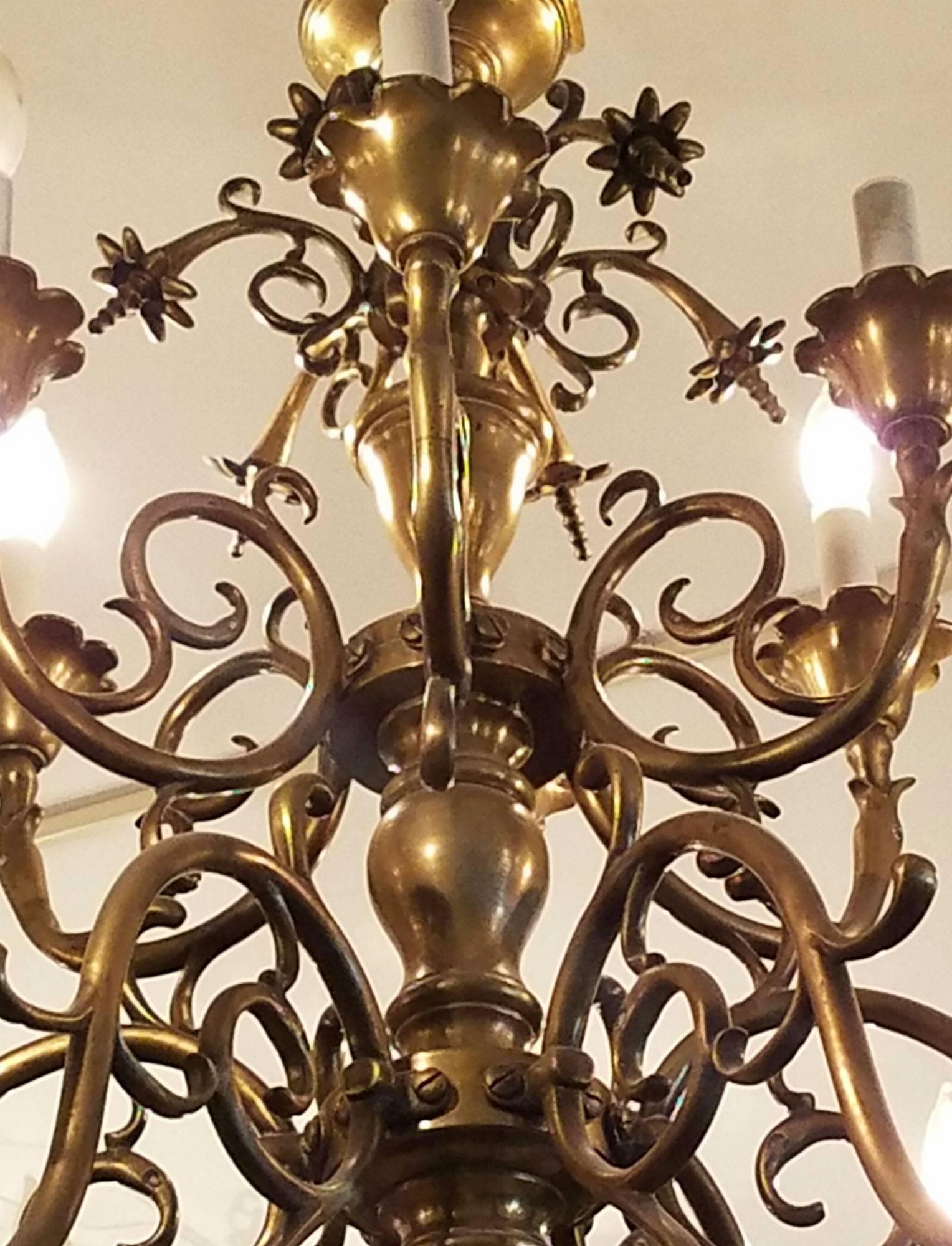 Large Dutch brass two-tier twelve-light chandelier with 's' curved arms, scalloped candle cups and decorative flower heads.