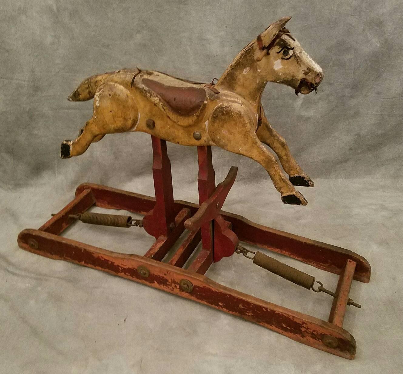 Carved wood painted and stained spring action rocking horse on a platform base.