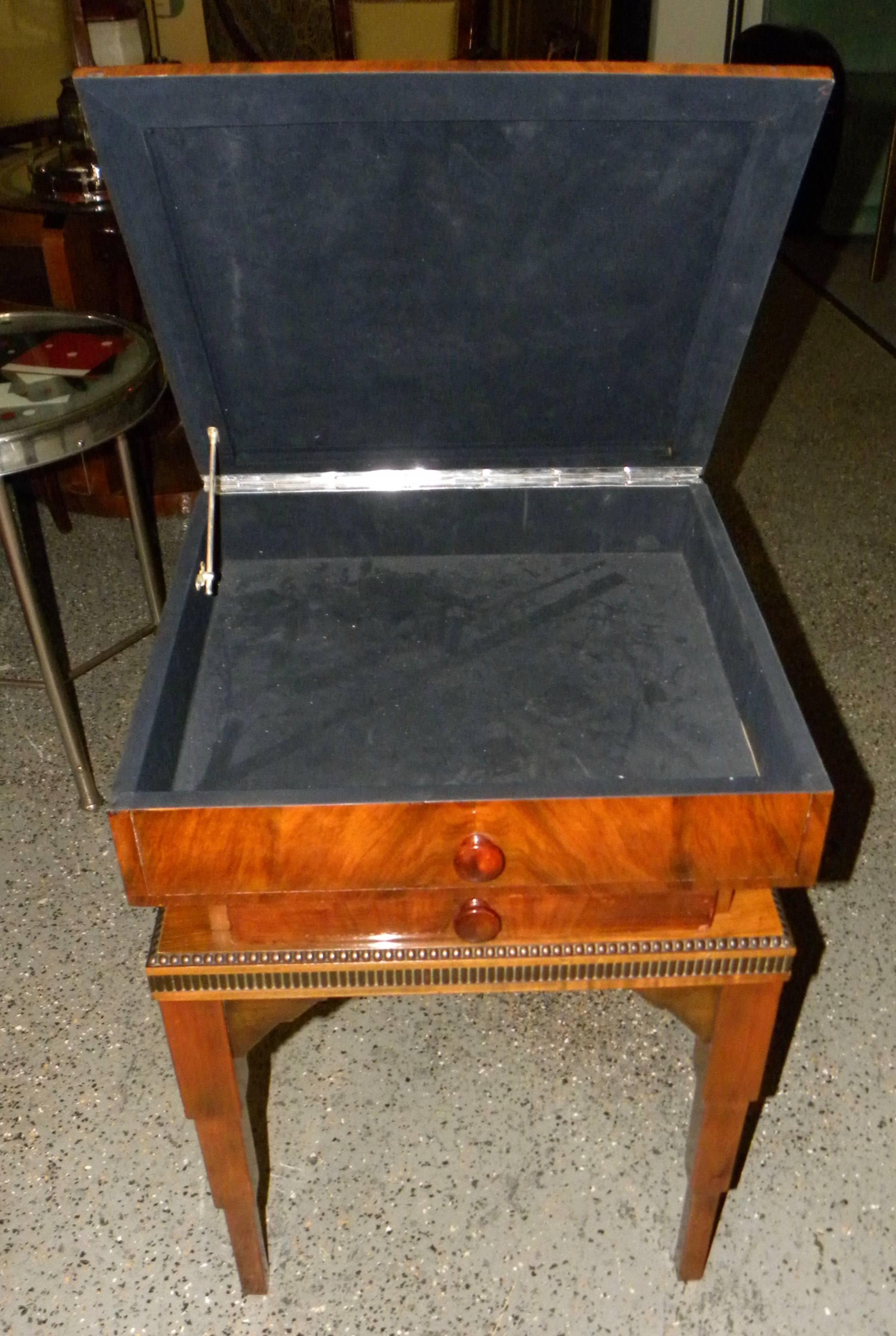 Art Deco storage table with top opening and storage drawer. Fantastic walnut wood with stair-stepped legs and nice edge details along the edges of the piece. The gorgeous bookmatched veneer on the top makes this quite an exceptional piece of