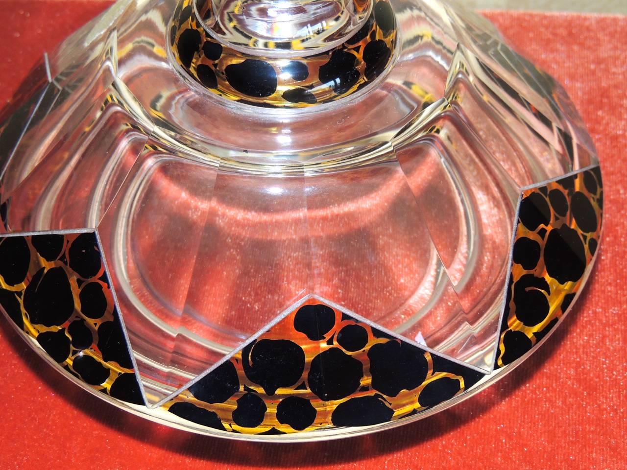 A most unique Czech Bohemian Art Deco glass decanter with a zig zag pattern embellished with a leopard like design in amber and black. The decanter is faceted, graceful and has an impressive stopper with the matching pattern.

We once heard