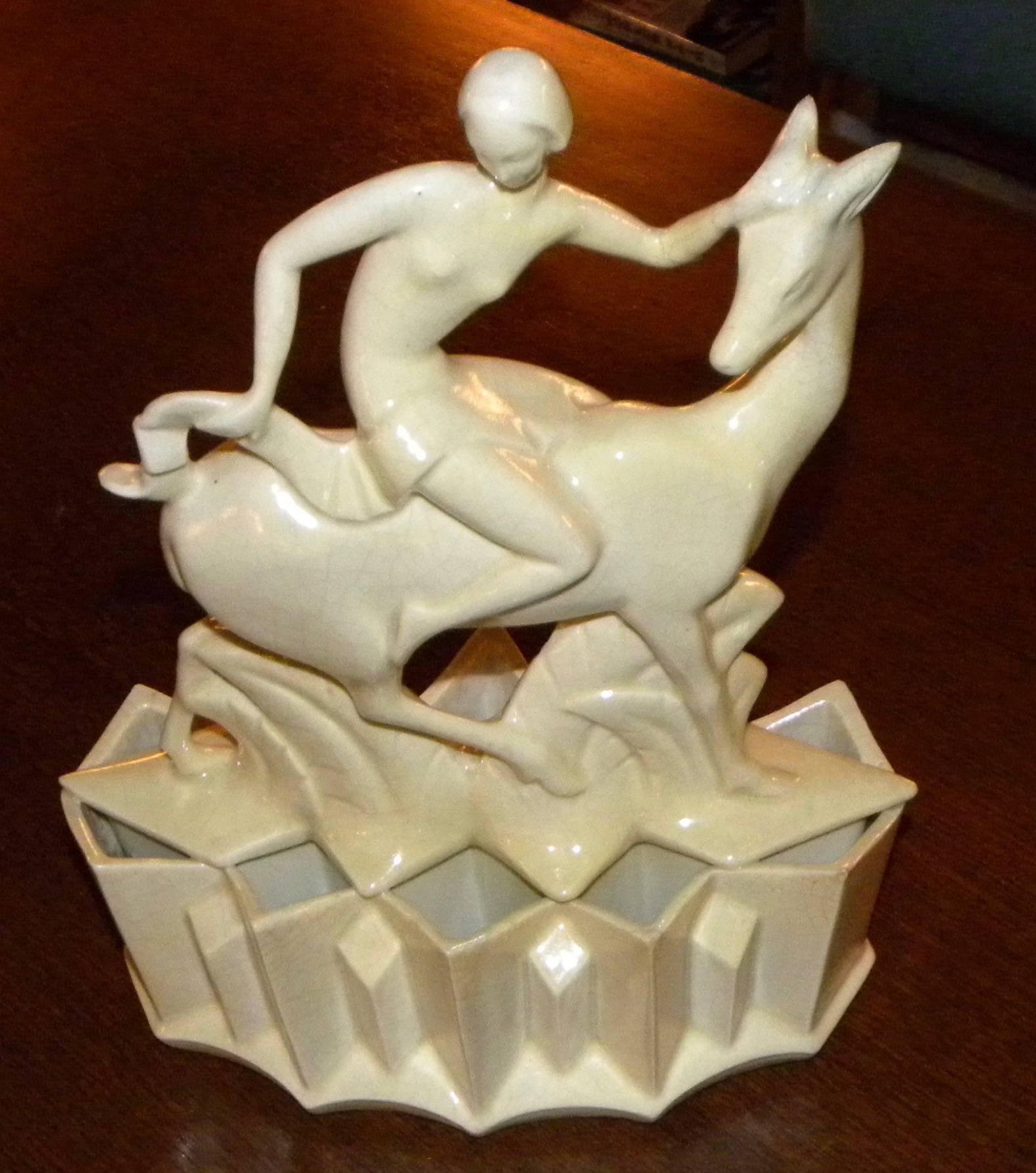 This stunning French crackle-glazed cubist figure is compelling and unique. The stylized female form sitting on top of the stylized antelope is supported by a sculpted geometric base. This piece has all the earmarks of a great European inspired